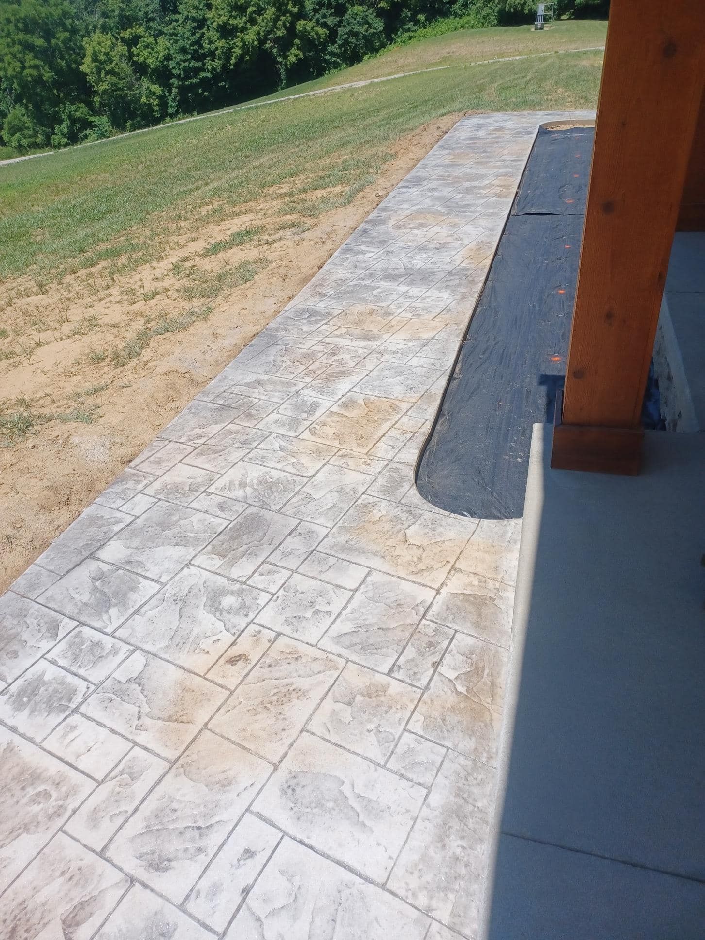 A concrete walkway leading to a grassy hillside