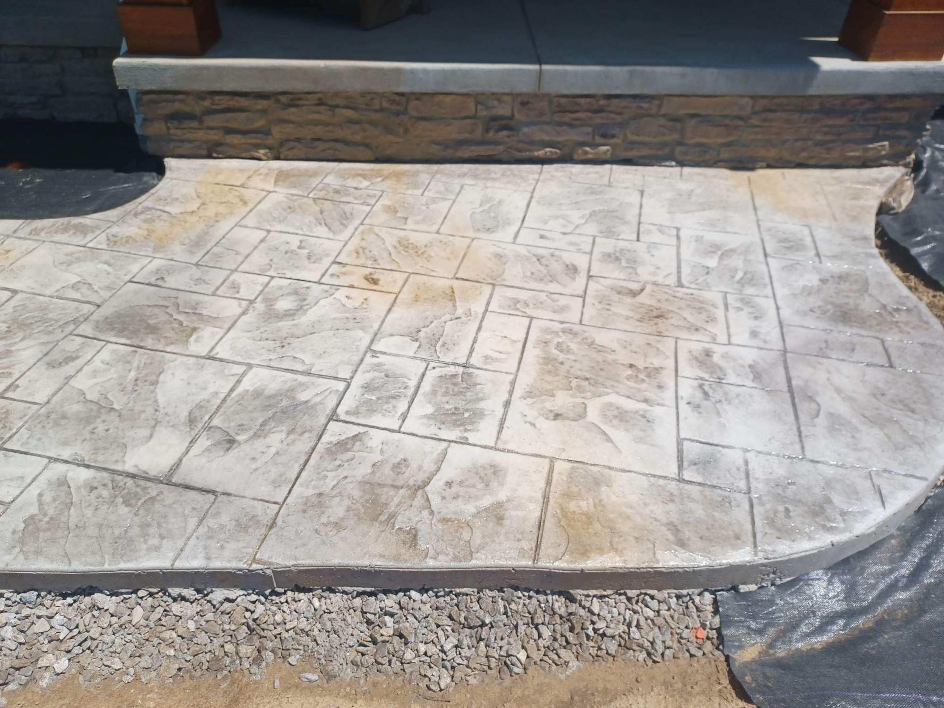 A concrete walkway with a stone wall in the background