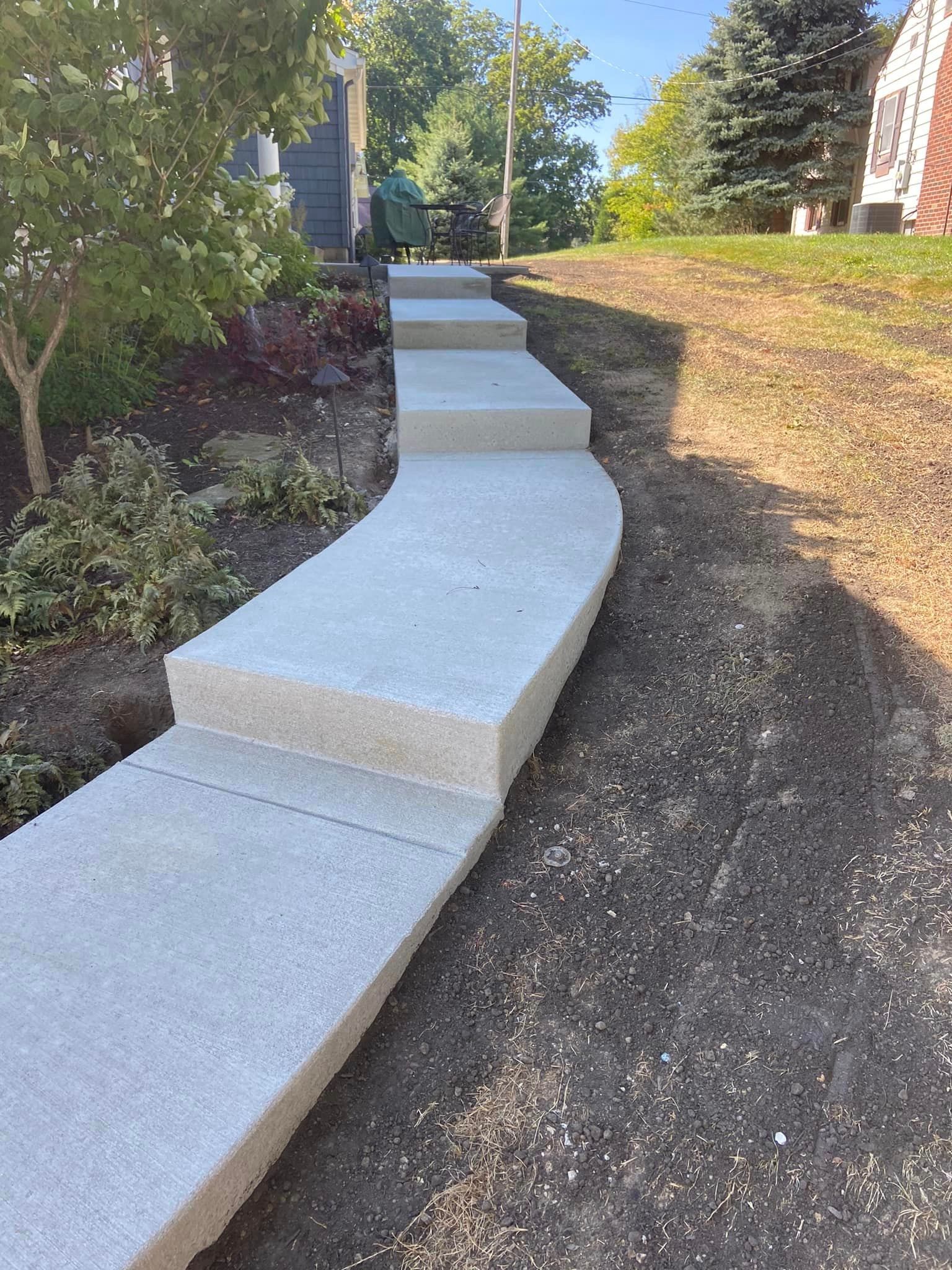 A concrete walkway with stairs leading up to a house.