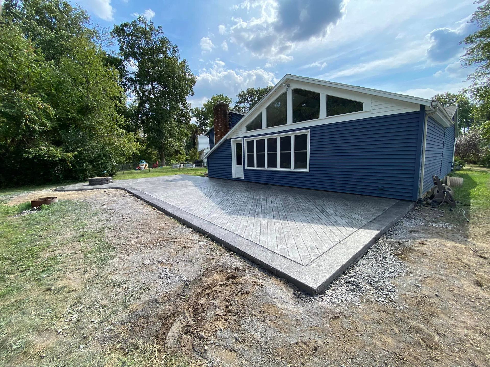 A blue house with a concrete patio in front of it.