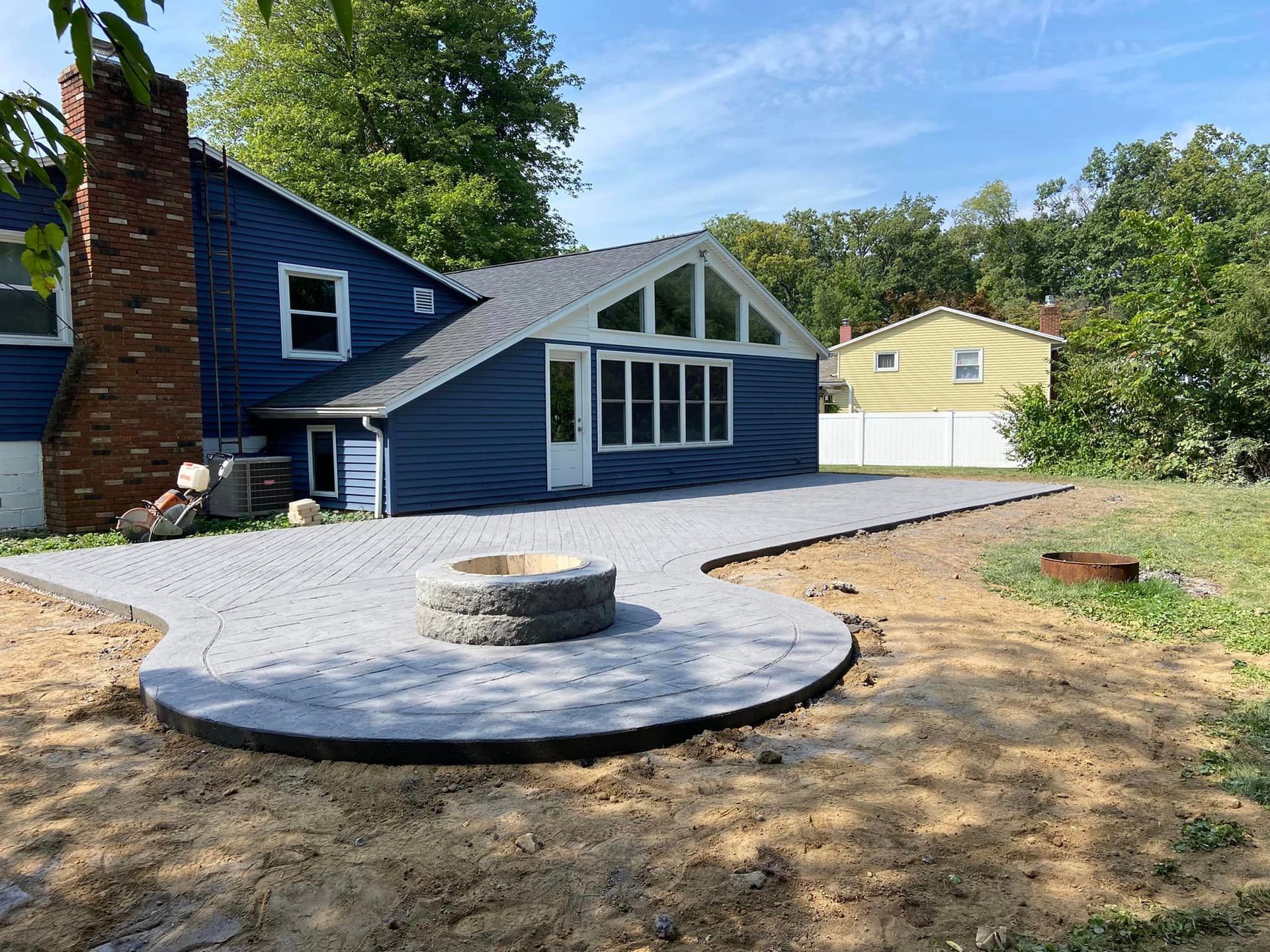 A blue house with a fire pit in front of it.