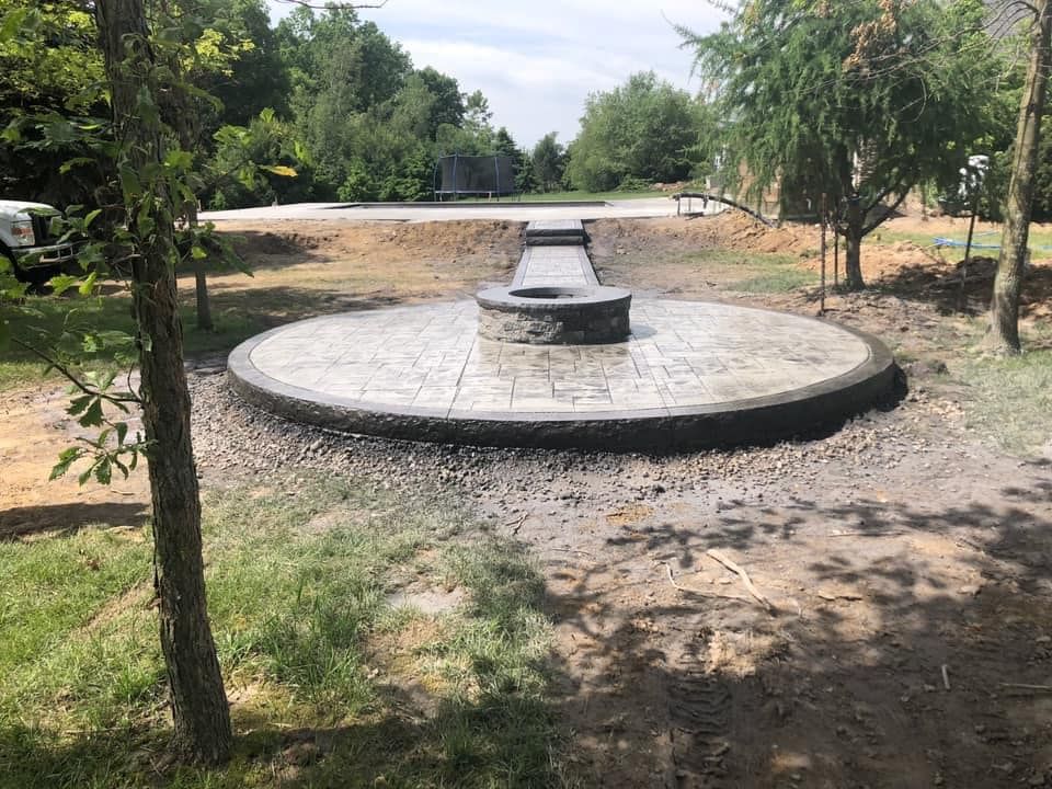 A fire pit is sitting in the middle of a lush green field.