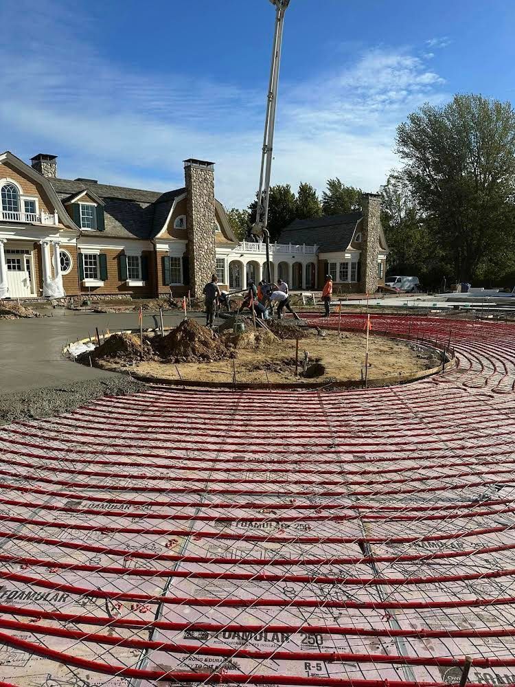 A large house is being built with a lot of red pipes in front of it.
