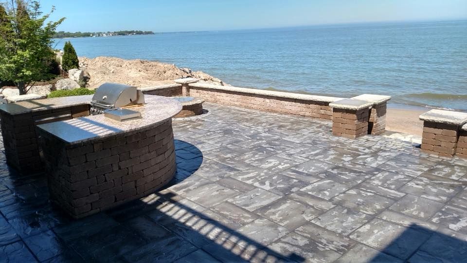 A patio with a grill and a view of the ocean.