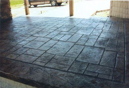 A concrete driveway with a car parked in the background