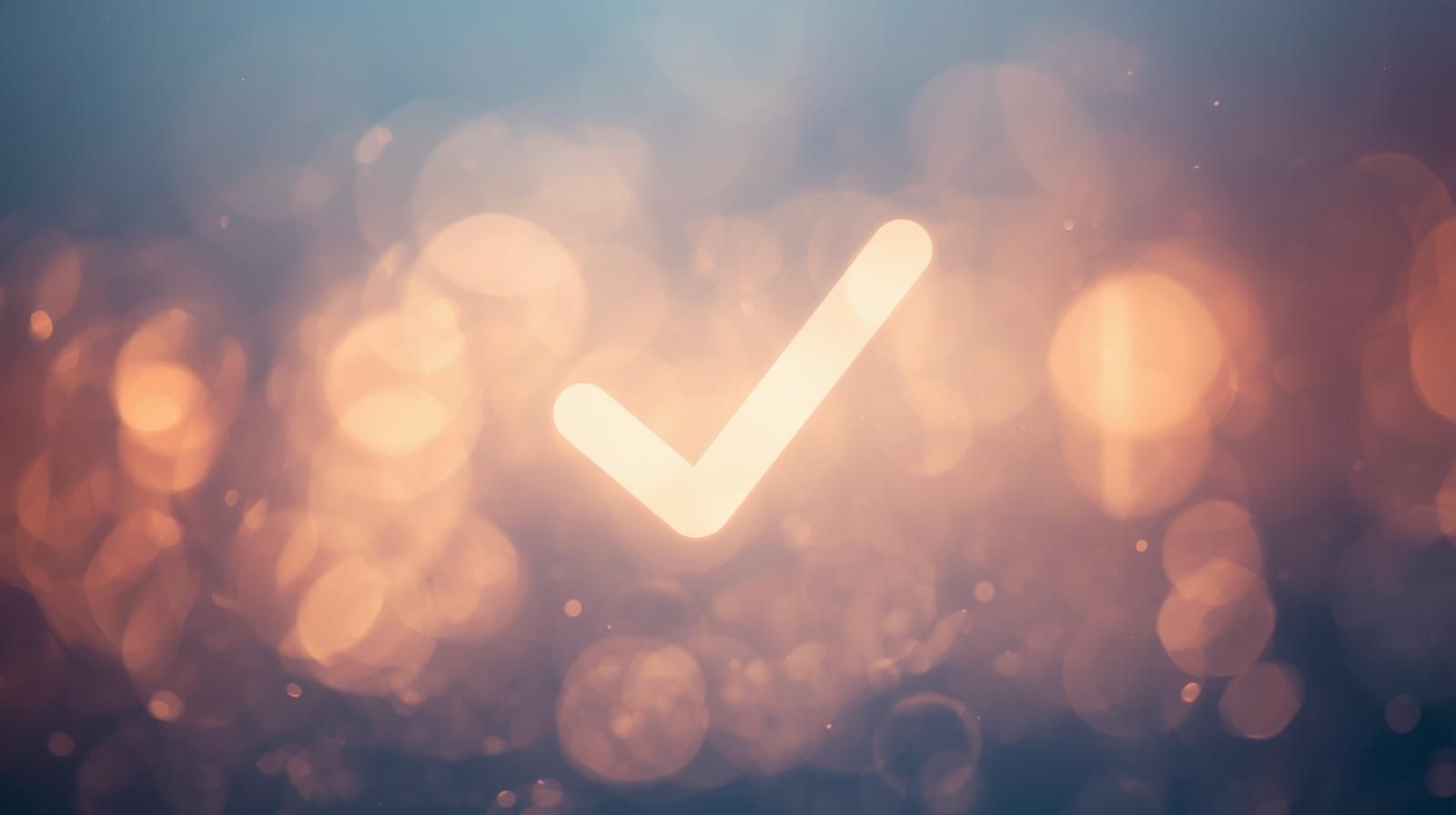 Glowing check mark against a blurred, golden bokeh background.