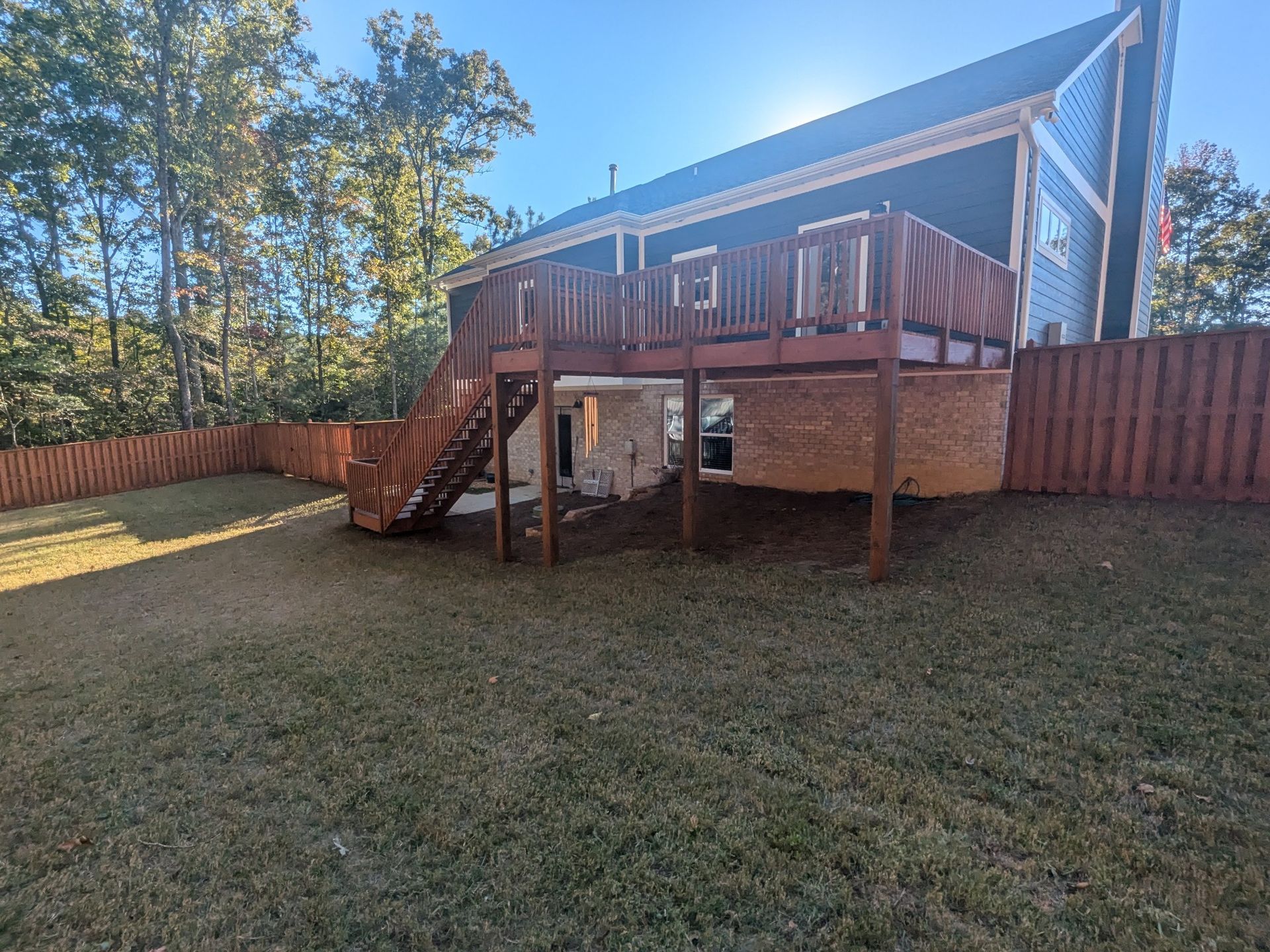 A large house with a large deck and stairs in the backyard.