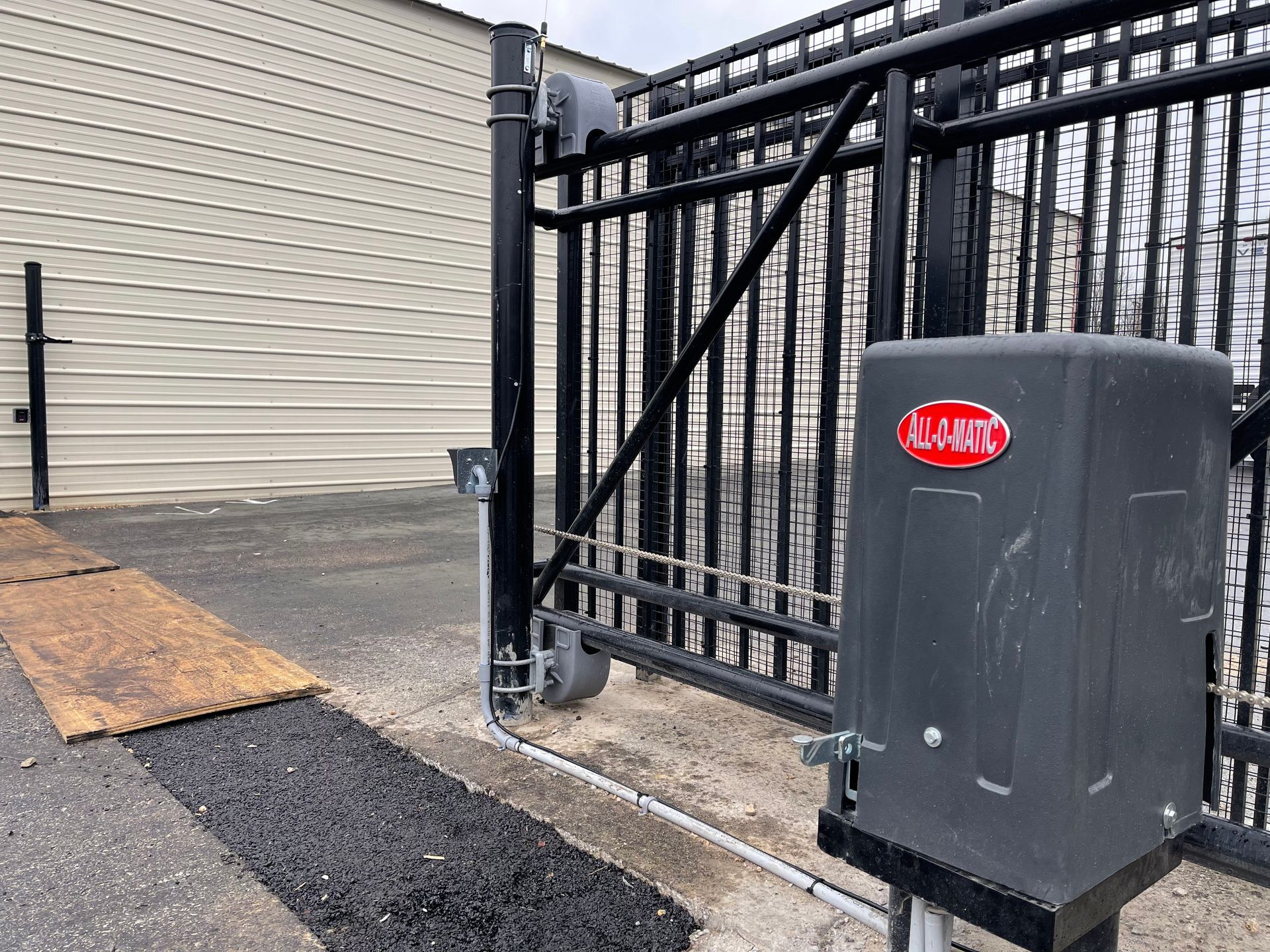 A black sliding gate with a gray box in front of it.