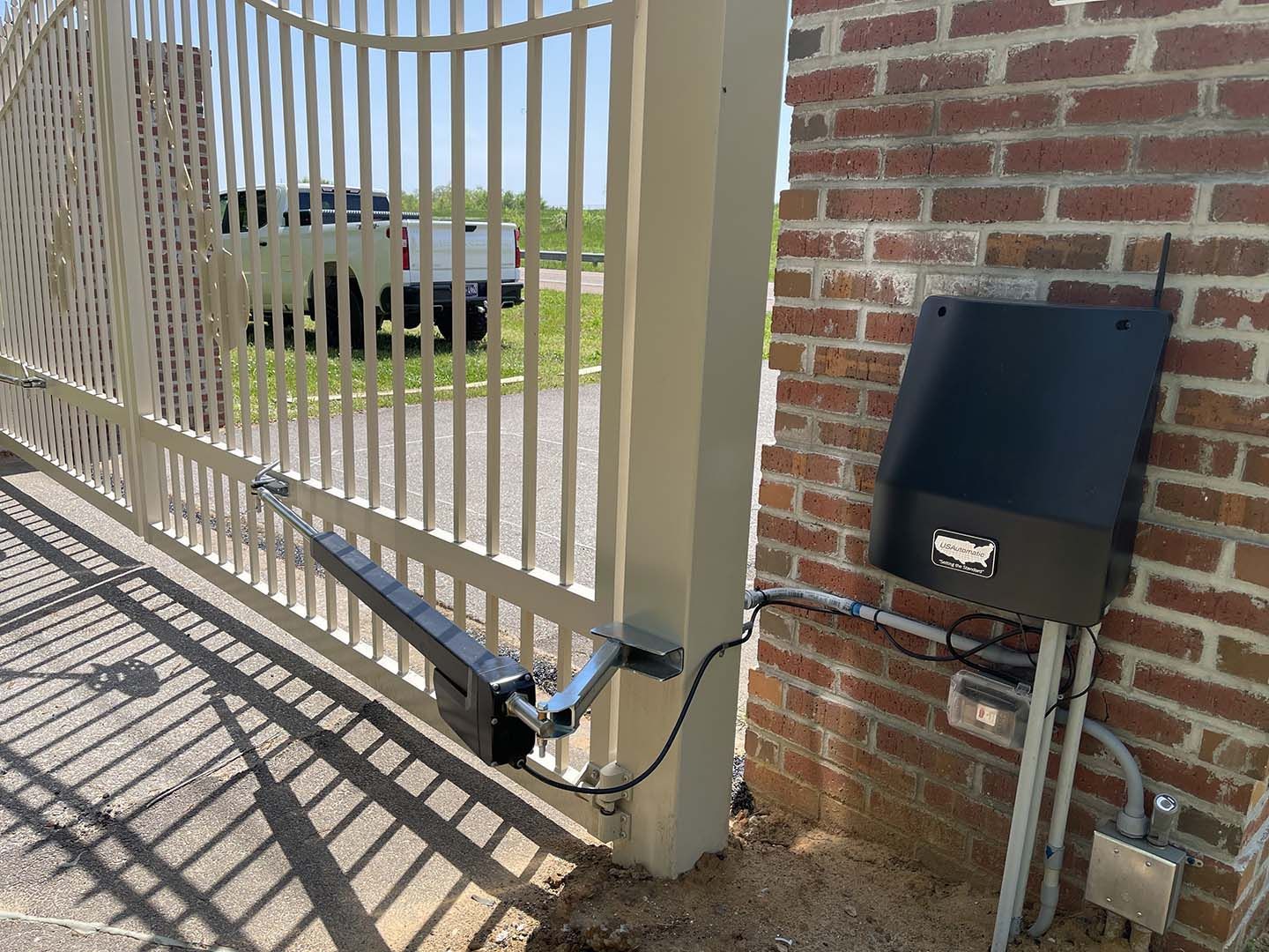 A gate with a motor attached to it is sitting next to a brick wall.
