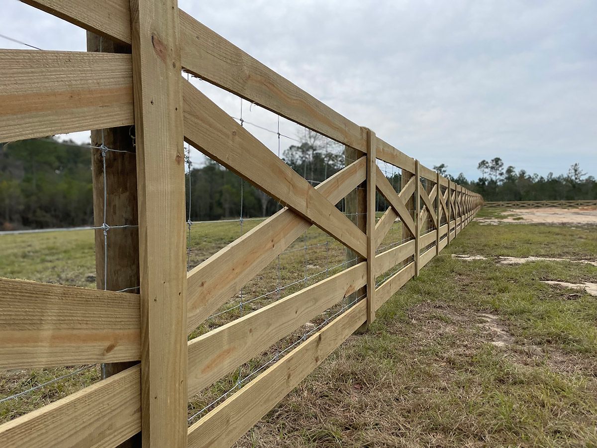 Wooden fence with cross supports in a field on an overcast day.