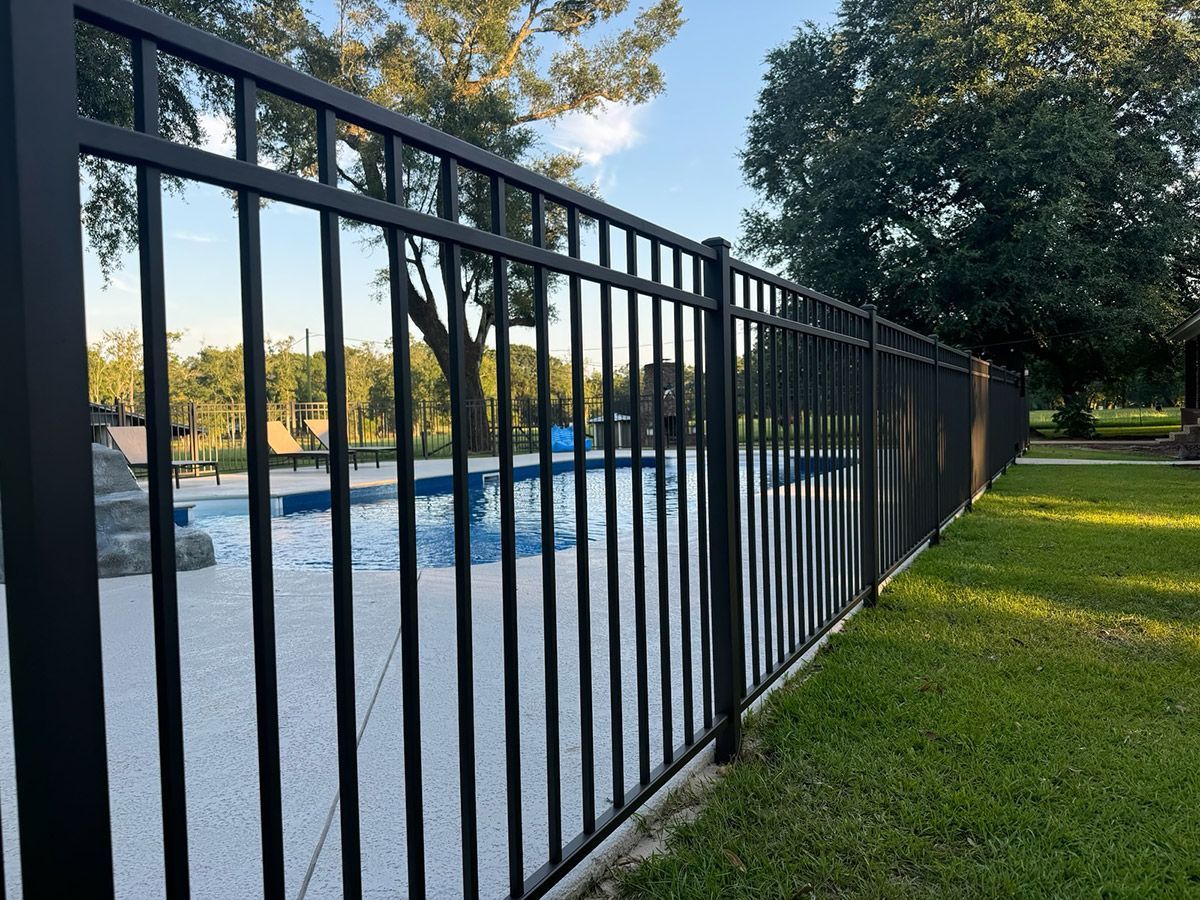A black metal fence surrounds a swimming pool.