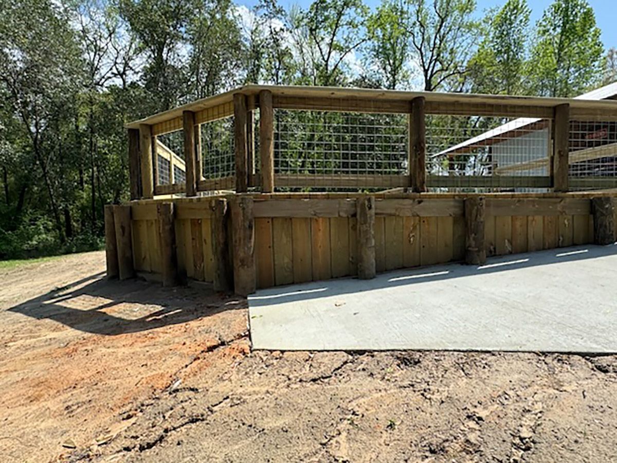 A wooden fence is sitting on top of a dirt field next to a concrete ramp.