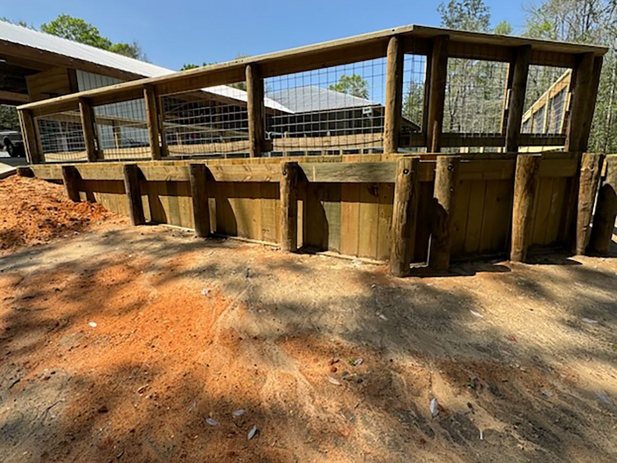 A wooden fence is sitting on top of a dirt field next to a building.