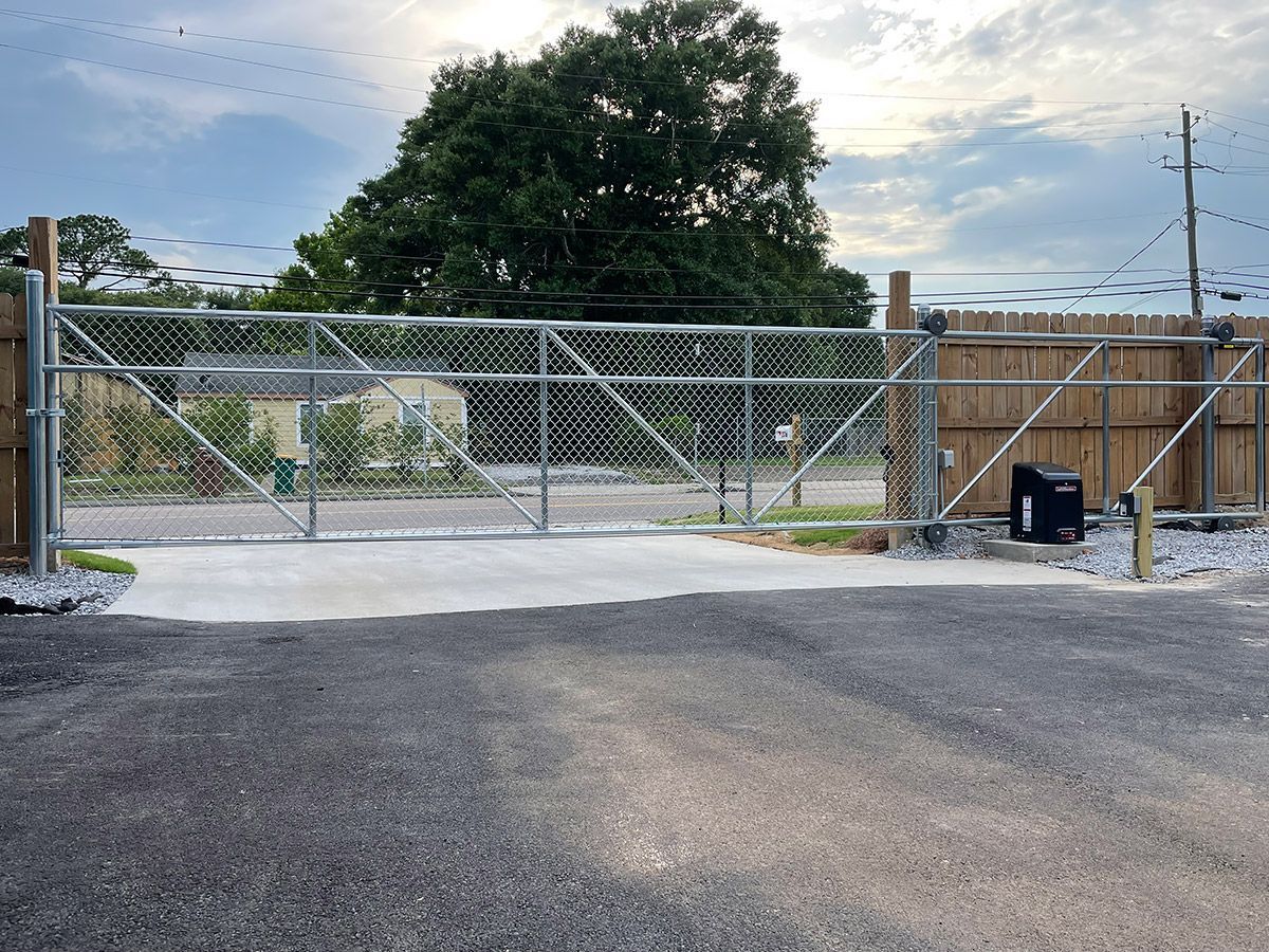 A chain link fence with a gate in the middle of a parking lot.