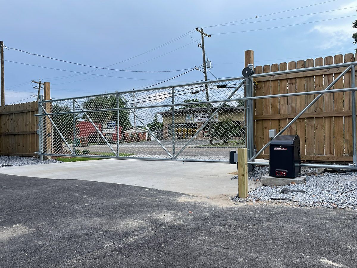 A chain link fence with a gate and a black box in front of it.