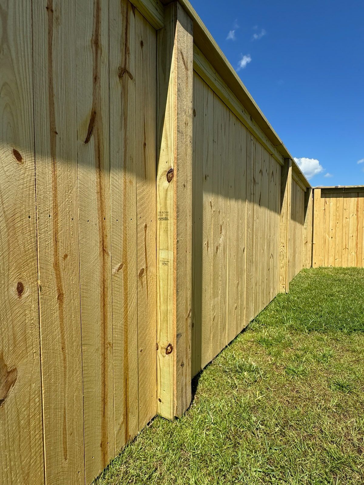 A wooden fence is sitting on top of a lush green lawn.