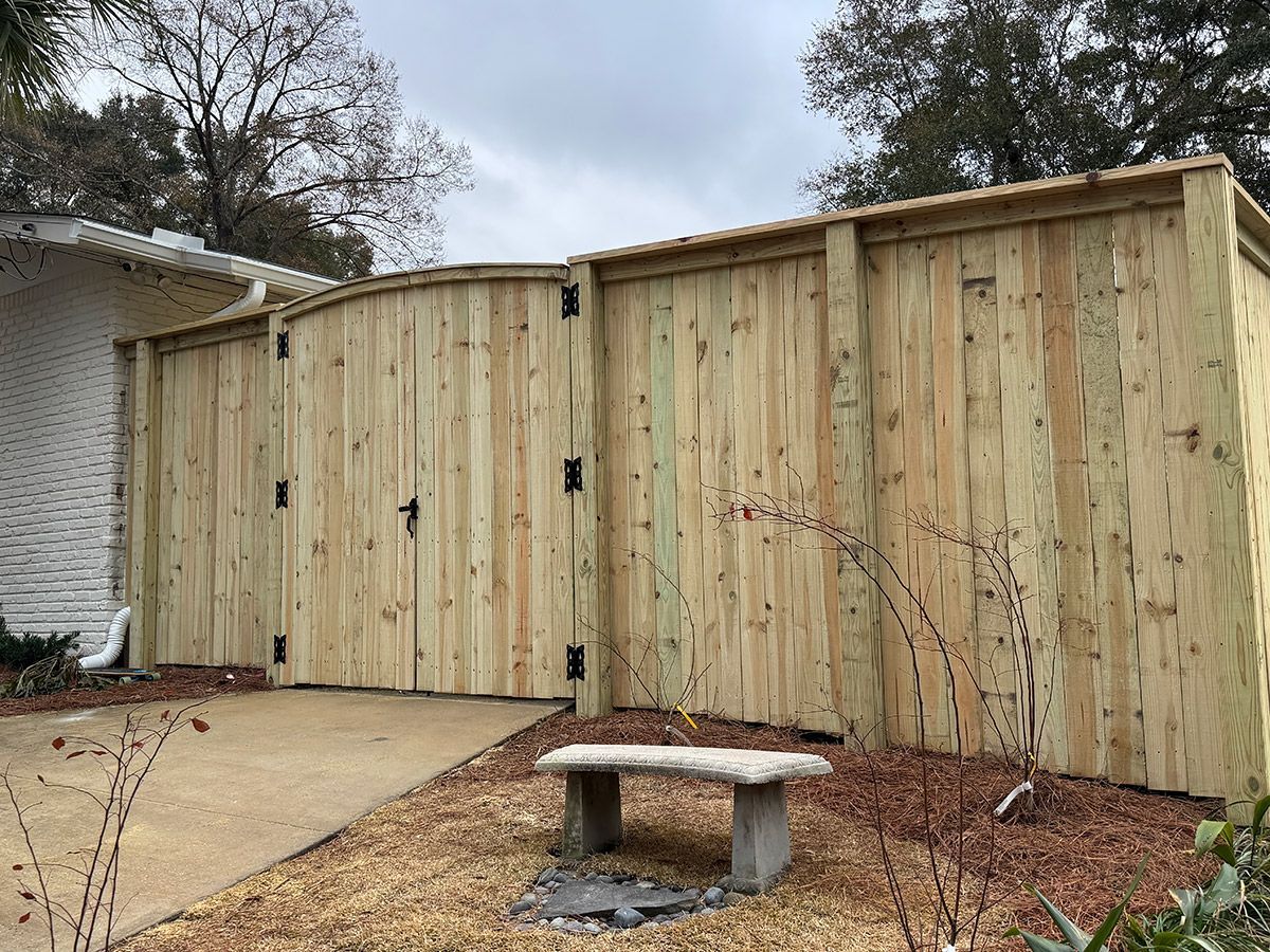 A wooden fence with a bench in front of it.