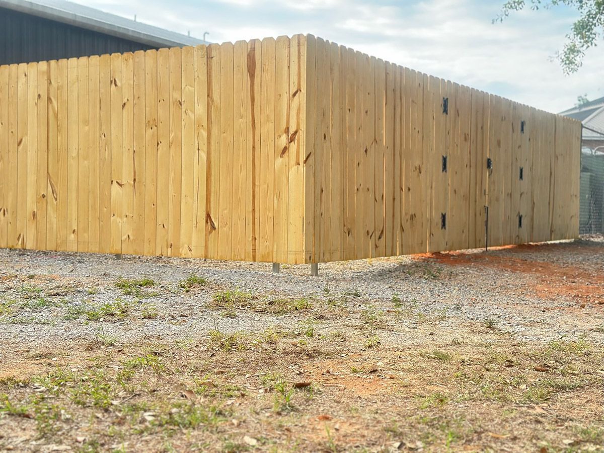 A large wooden fence is sitting in the middle of a dirt field.