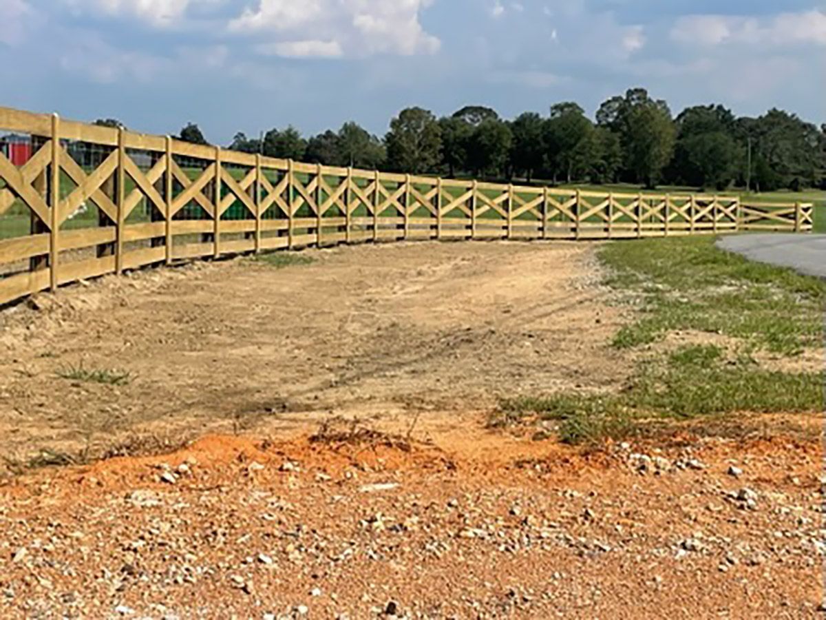 A wooden fence is sitting in the middle of a dirt field.