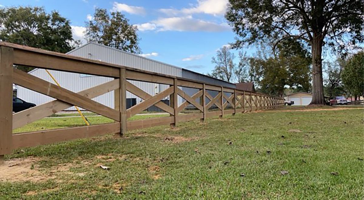 A wooden fence is sitting in the middle of a grassy field.