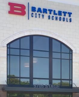 The front door of a house with a porch and plants in front of it.