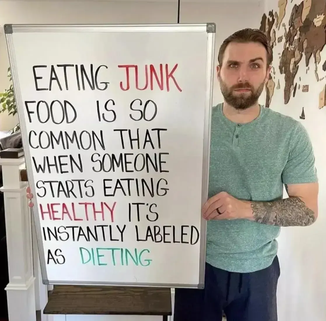 Man holding whiteboard with text about eating junk food being common.