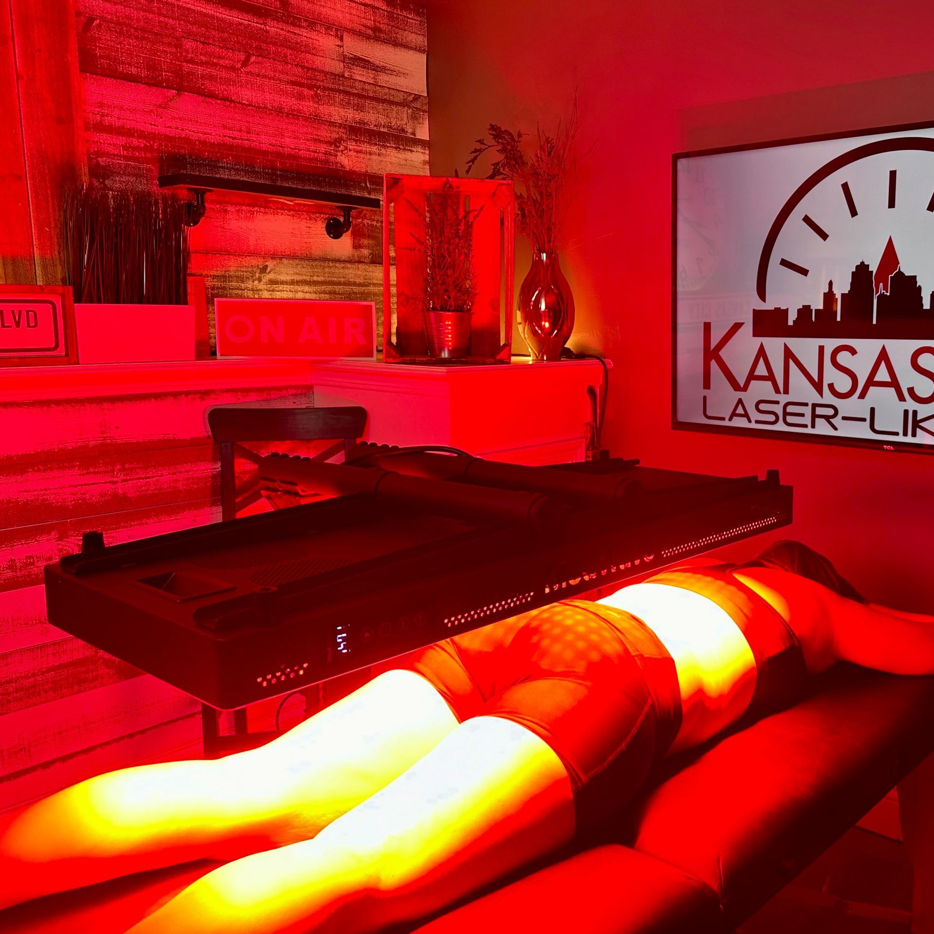 Woman receiving red light therapy treatment. Kansas Laser-Like sign in background.