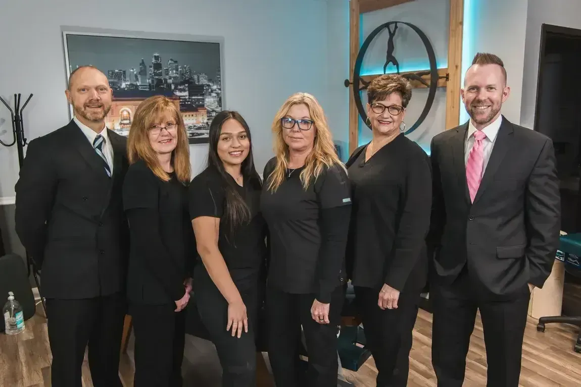 Un grupo de seis personas posa en una oficina. Visten ropa de trabajo y uniforme médico.