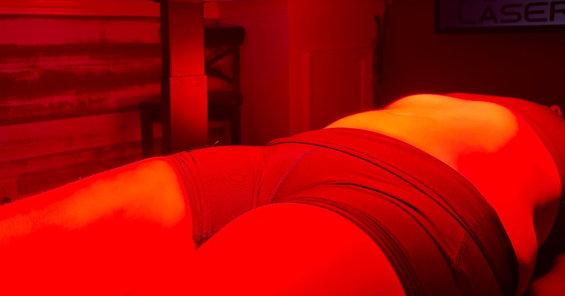 A person lying on a table in a room bathed in red light.