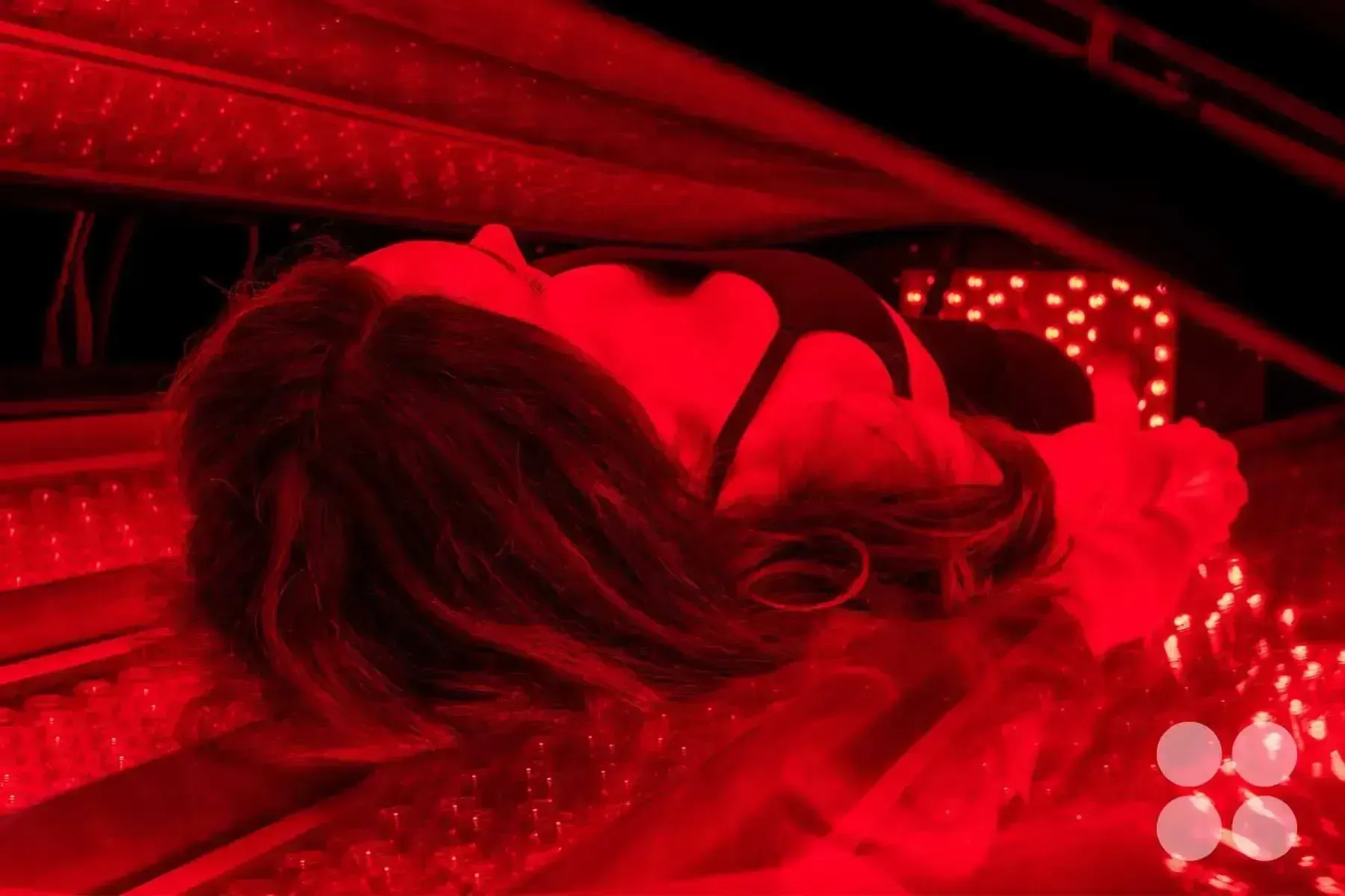 Woman lying down, lit by red light. Black top, looking upwards.