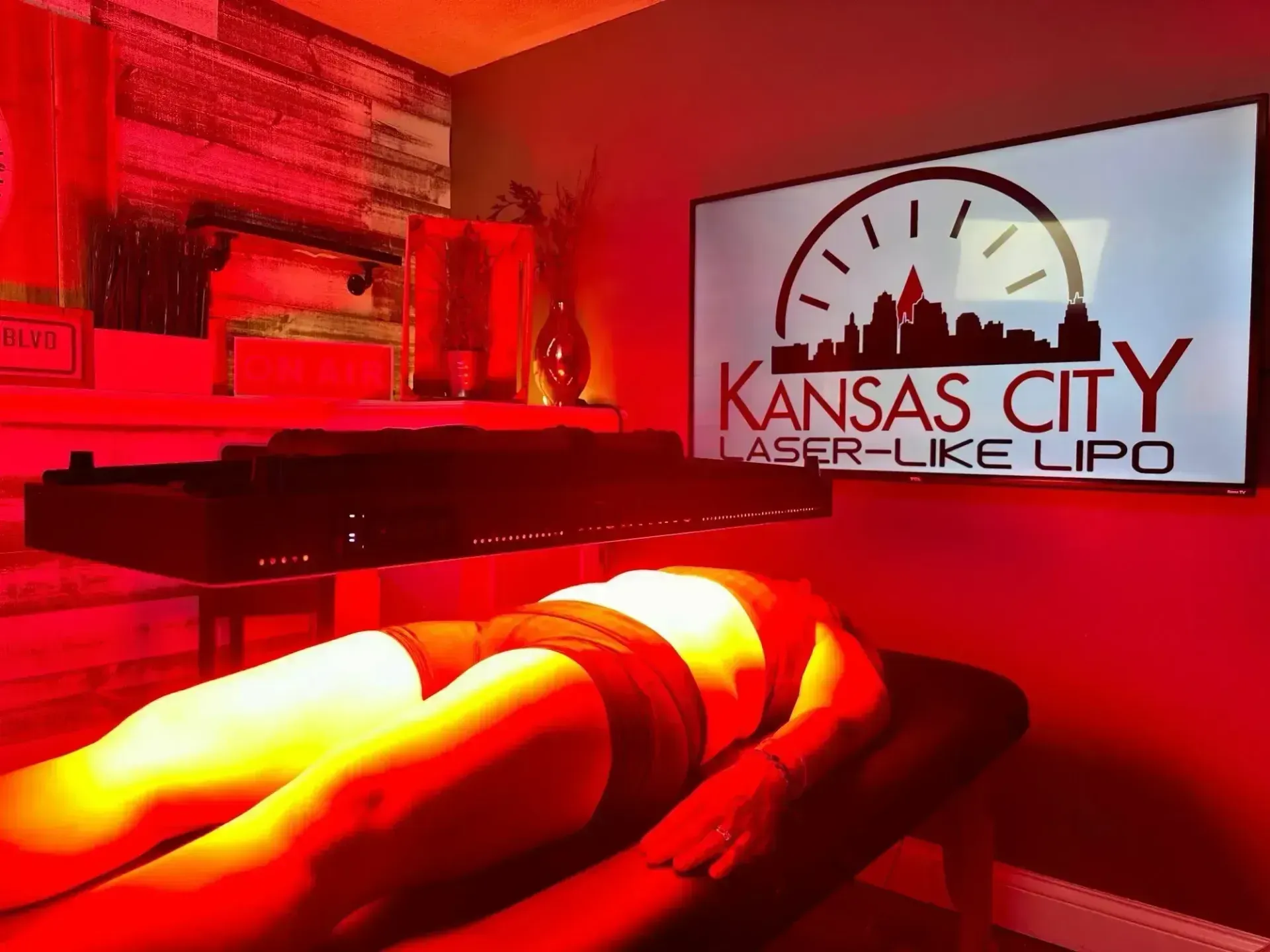 Person receiving laser-like lipo treatment. Red light illuminates the body in a Kansas City clinic.
