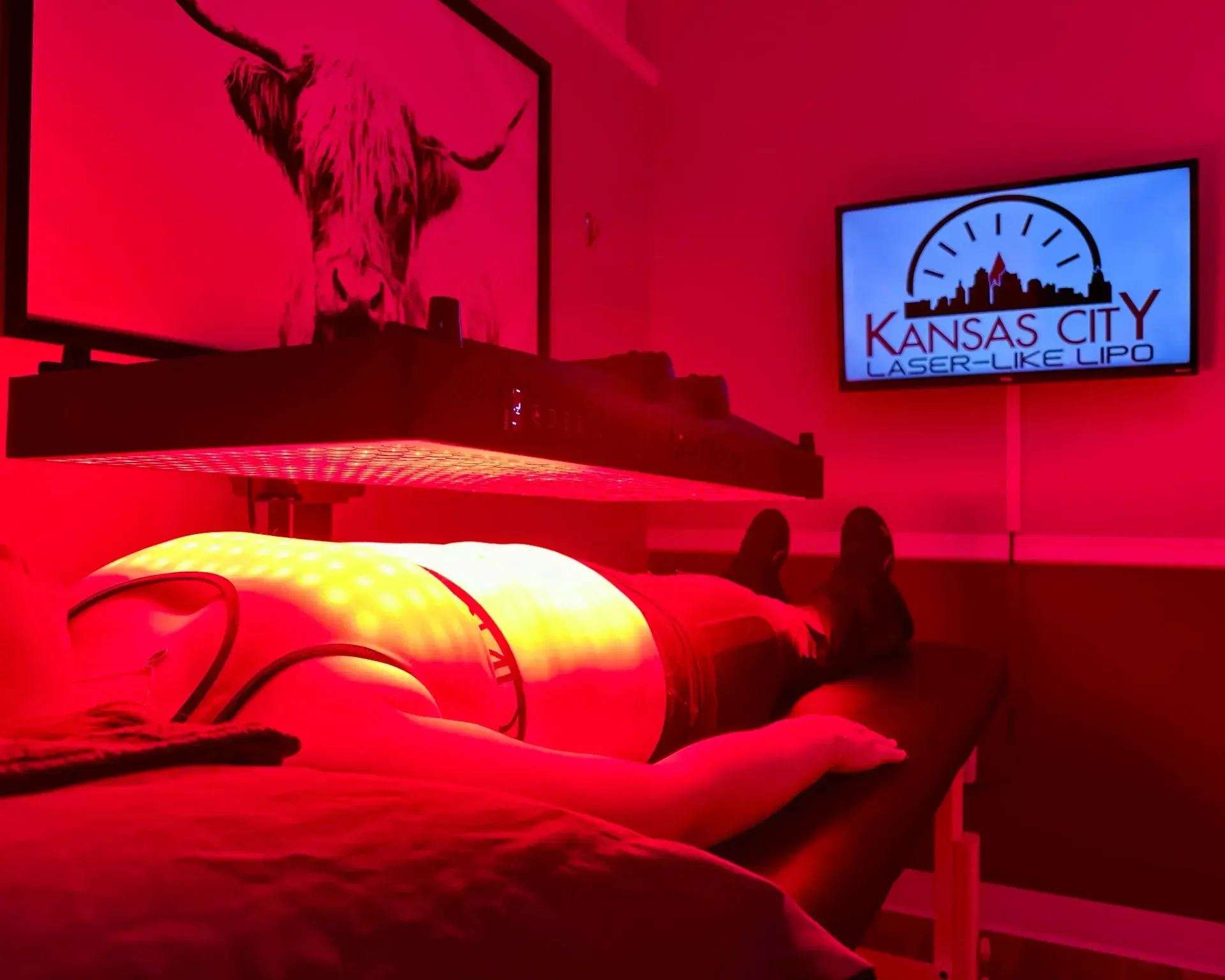 Person undergoing red light therapy at Kansas City Laser Lipo clinic. Red light illuminates the room.