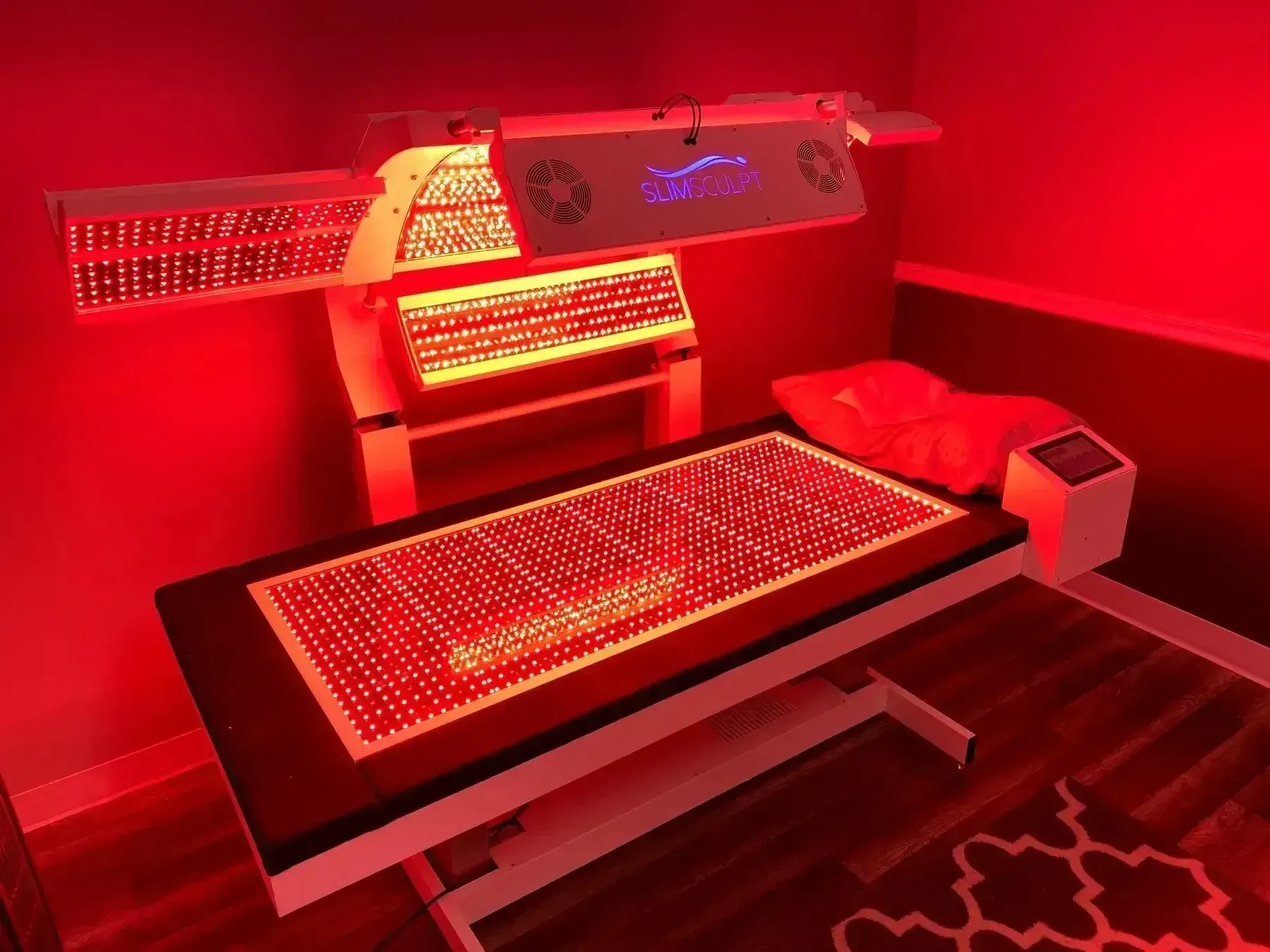 Red light therapy bed with overhead and bed-level light panels in a spa setting.