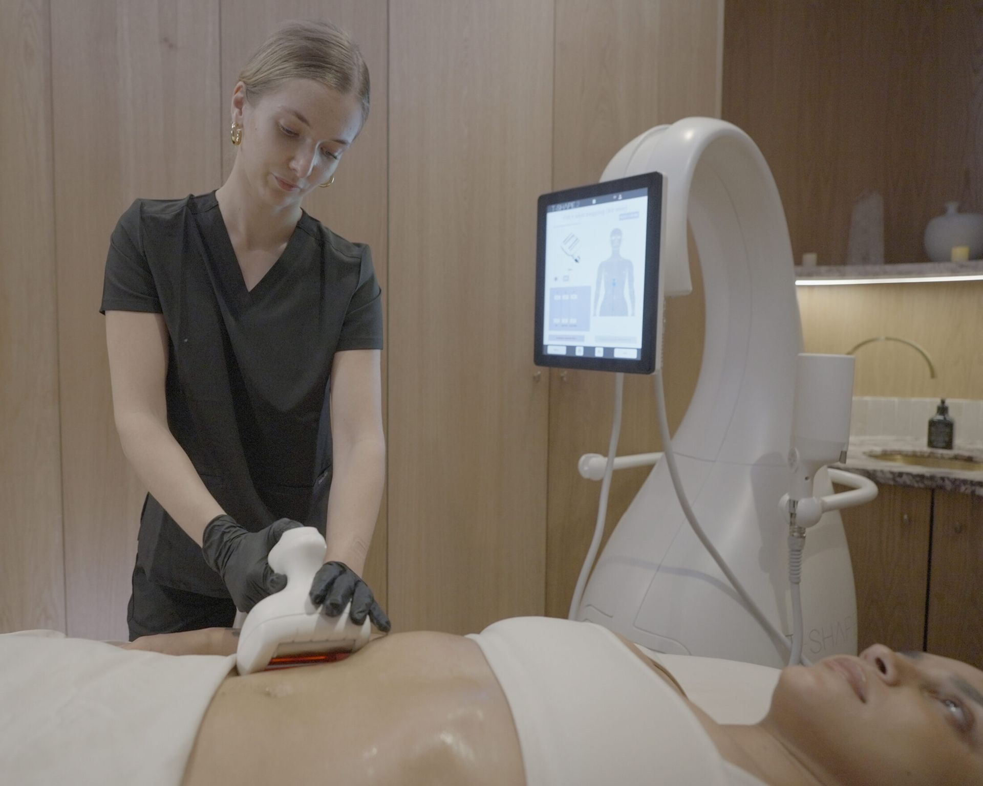 A woman receiving an Artemis T-Shape 2 session on her lower abdomen.