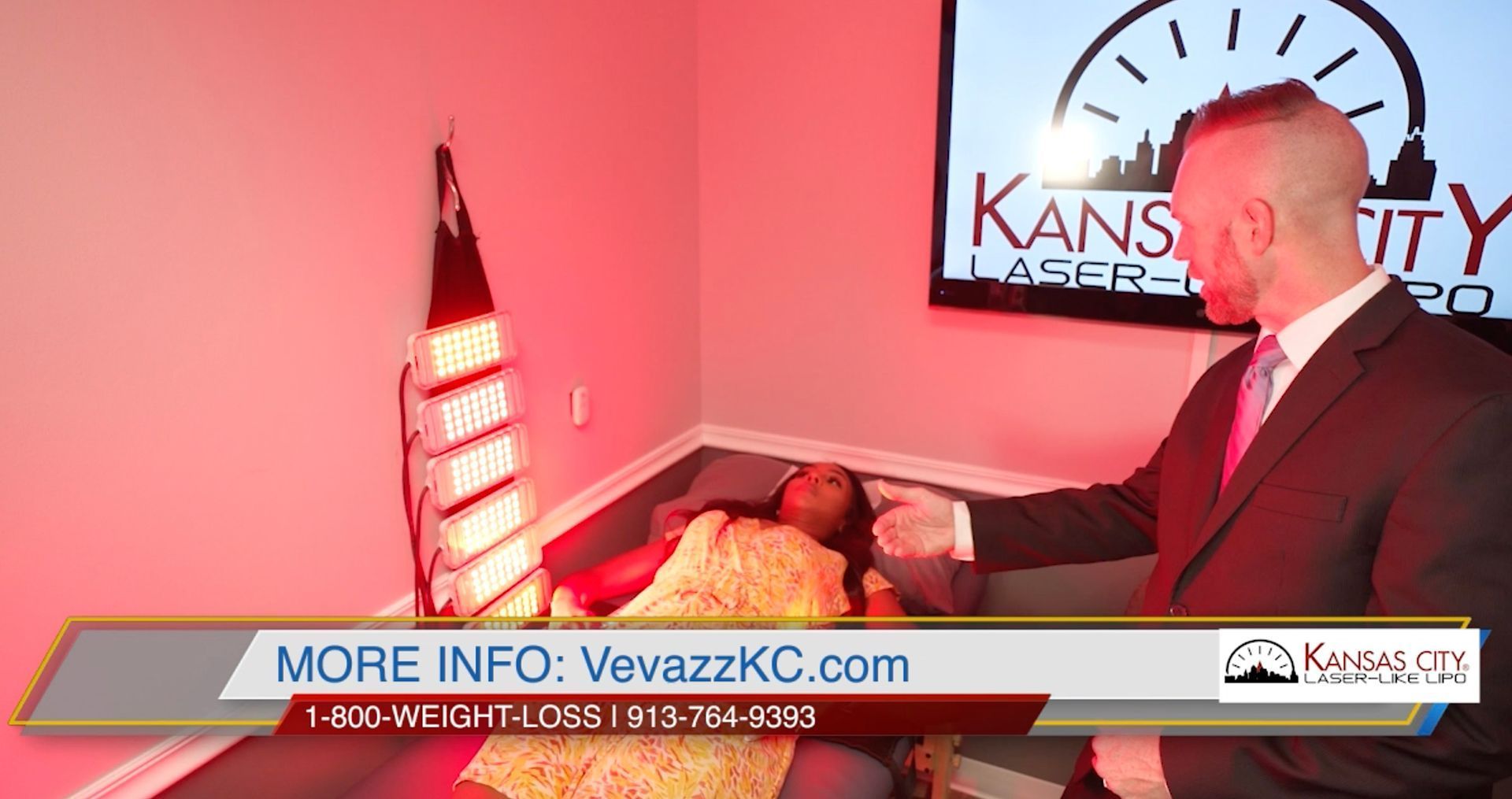 A man in a suit points to a person lying under red light therapy, with a logo in the background.