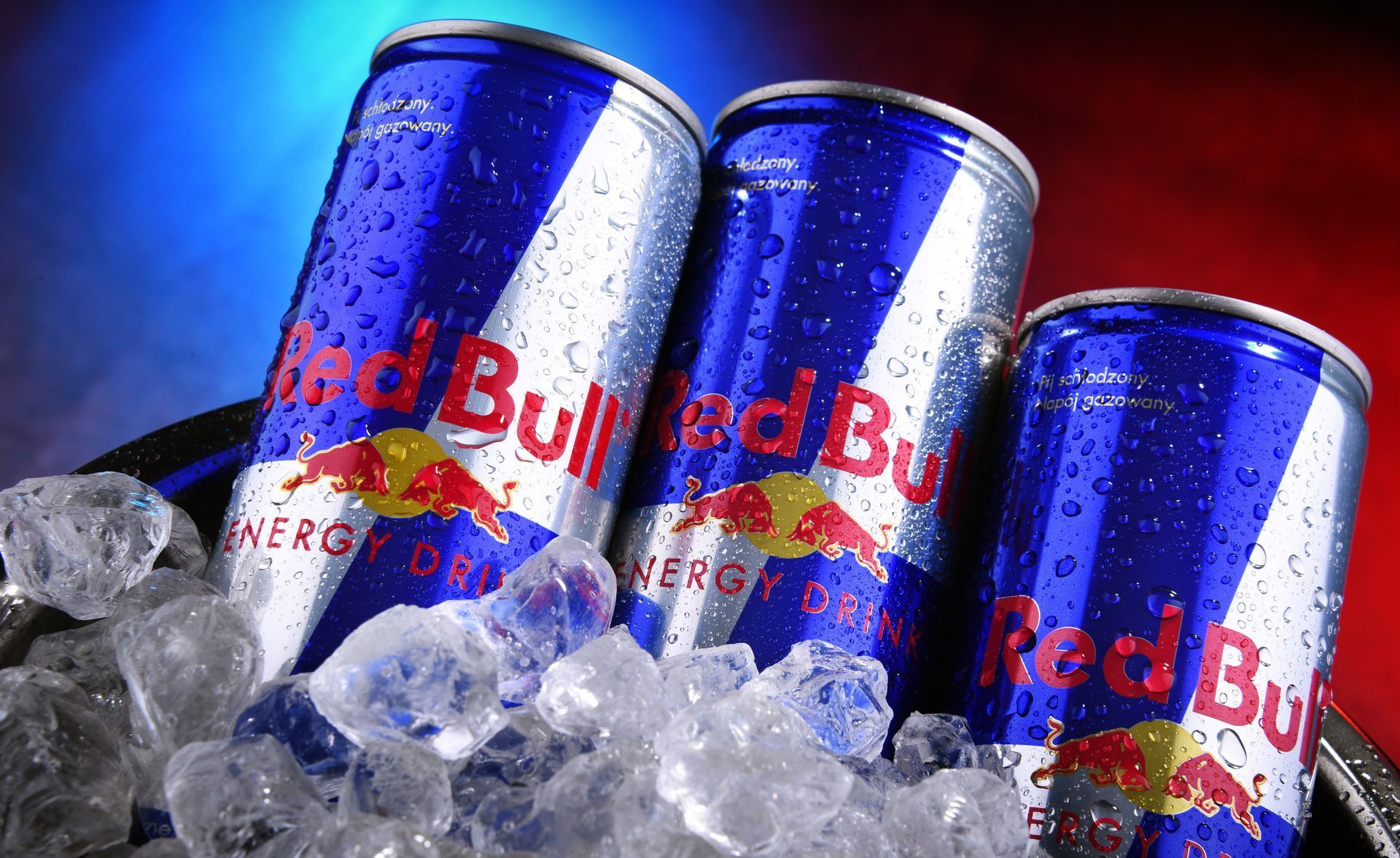 Three Red Bull energy drink cans, chilled in ice.