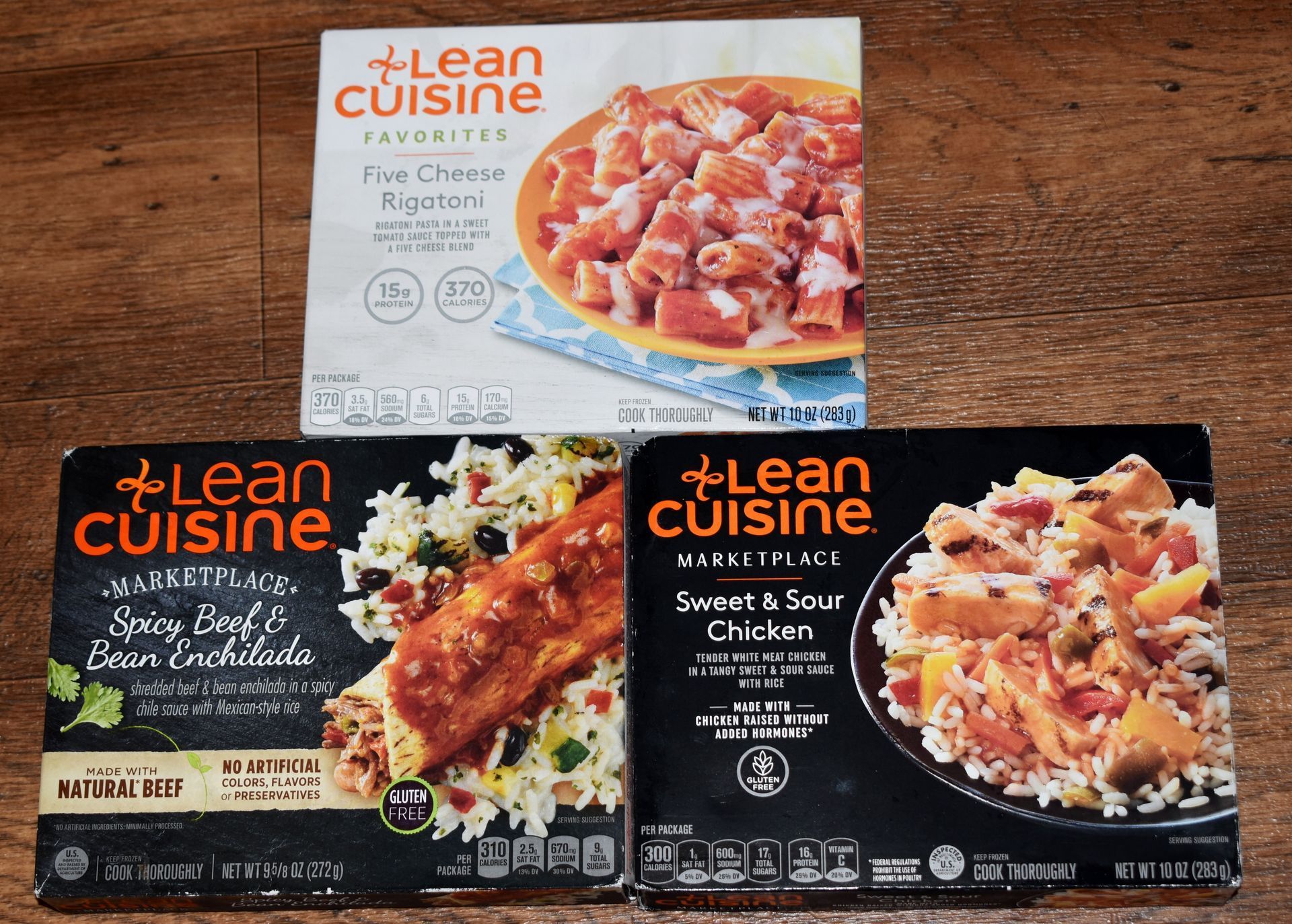 Three Lean Cuisine frozen meal boxes on a wooden surface.