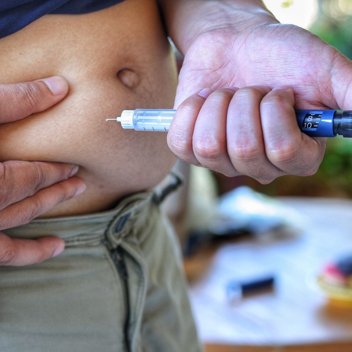 Person injecting insulin into their abdomen with an insulin pen.