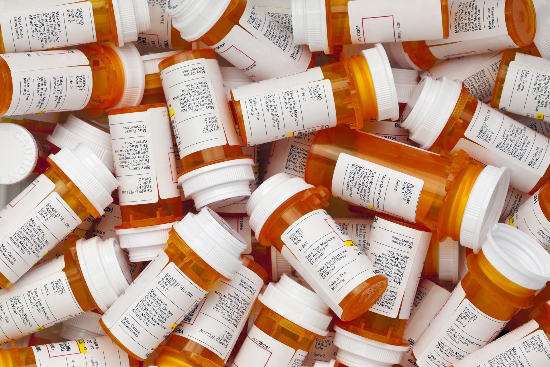 Orange prescription medicine bottles piled together.