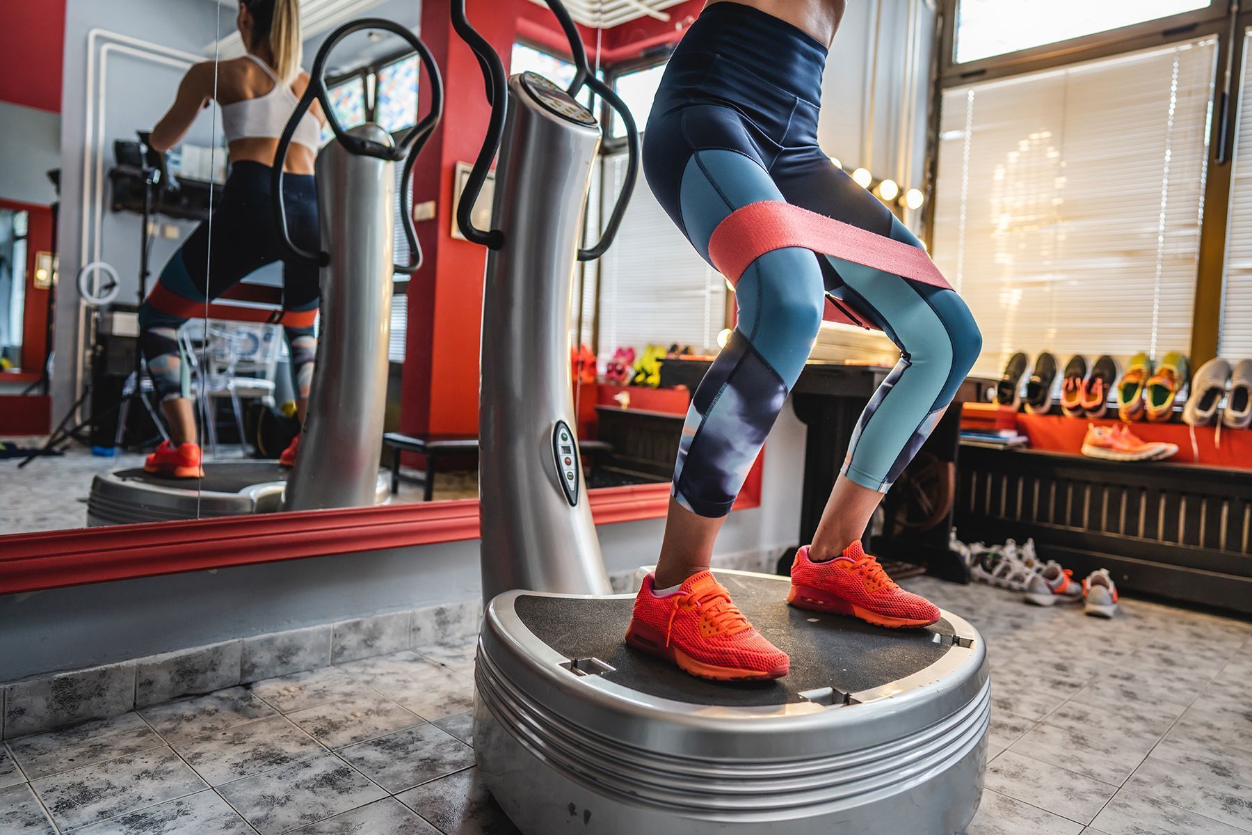 Woman exercising with resistance band on vibration plate in gym.