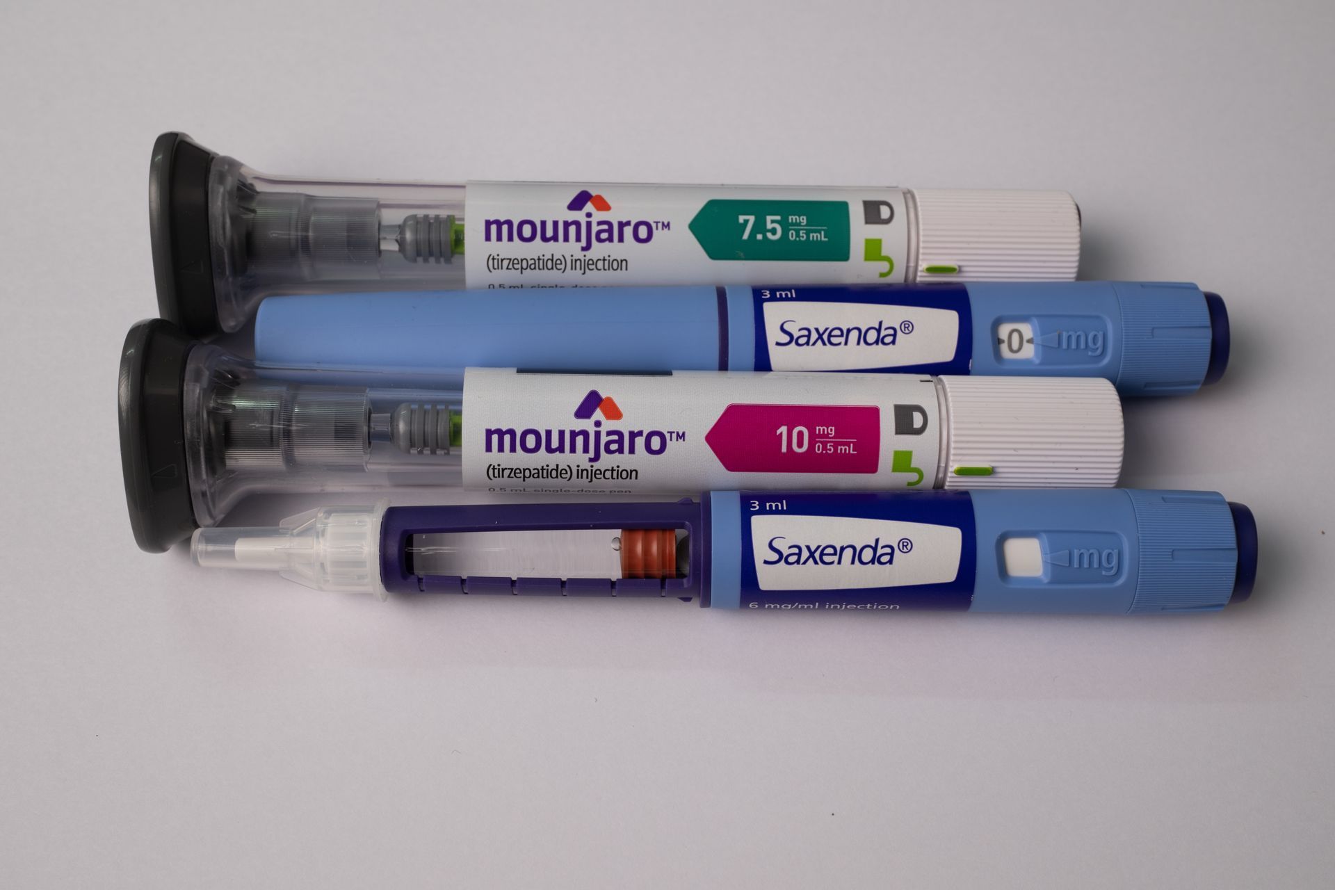 Two Mounjaro and two Saxenda prefilled injection pens on a white surface.