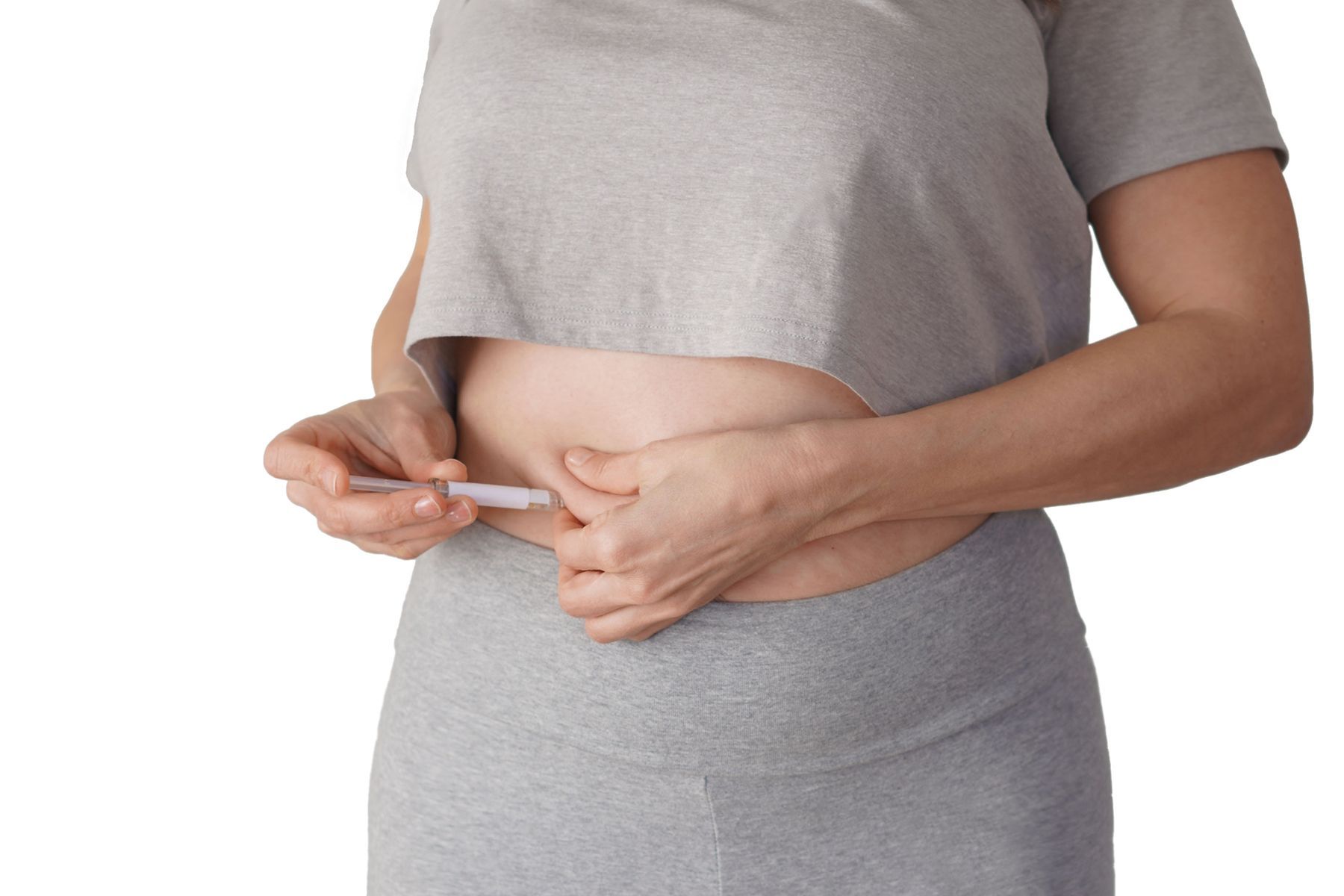 Person injecting medication into abdomen with syringe.