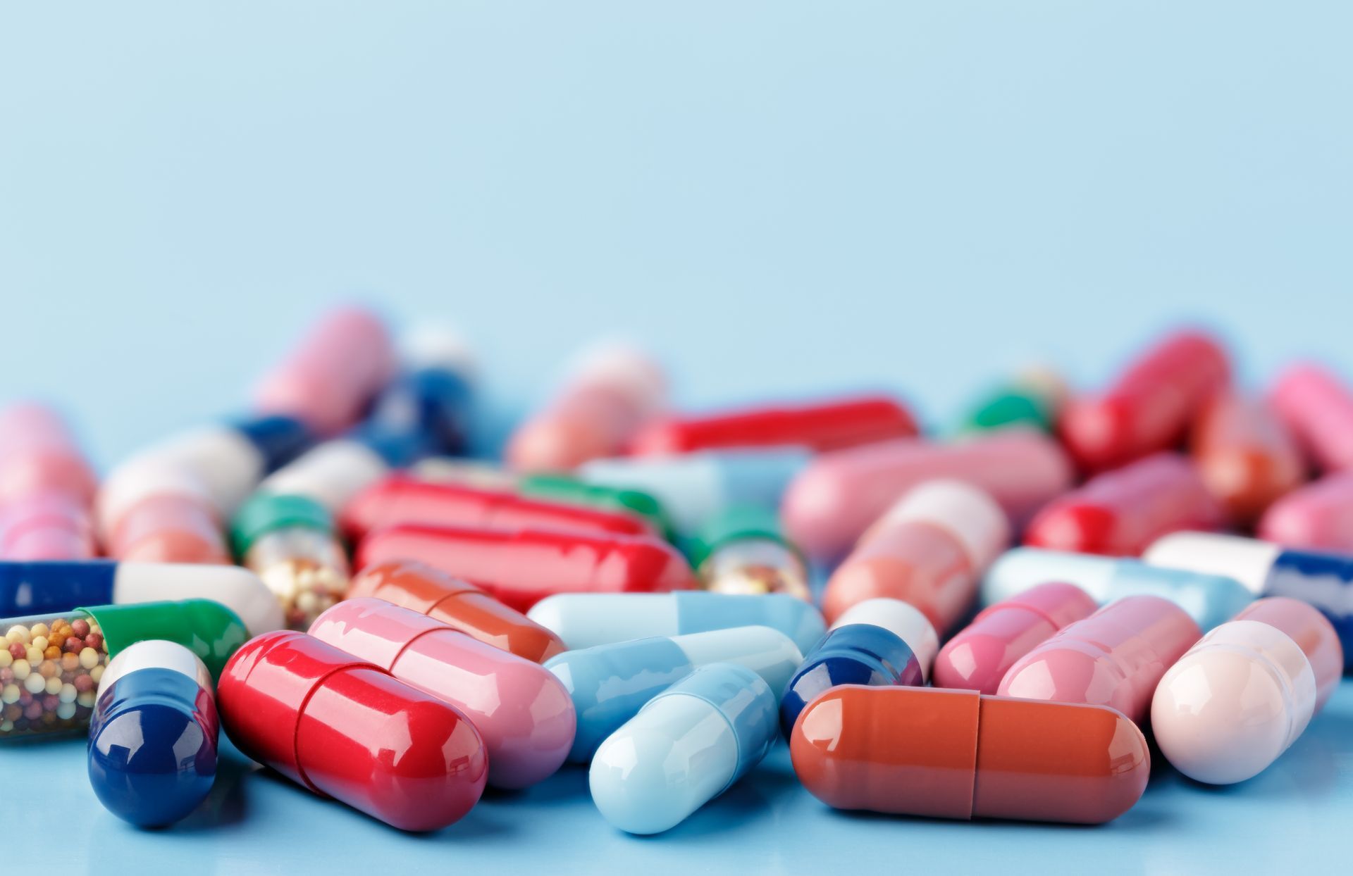 Assorted colorful capsules on a light blue surface.