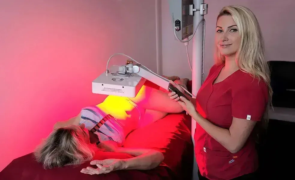 Woman administering red light therapy to a patient in a medical spa setting.