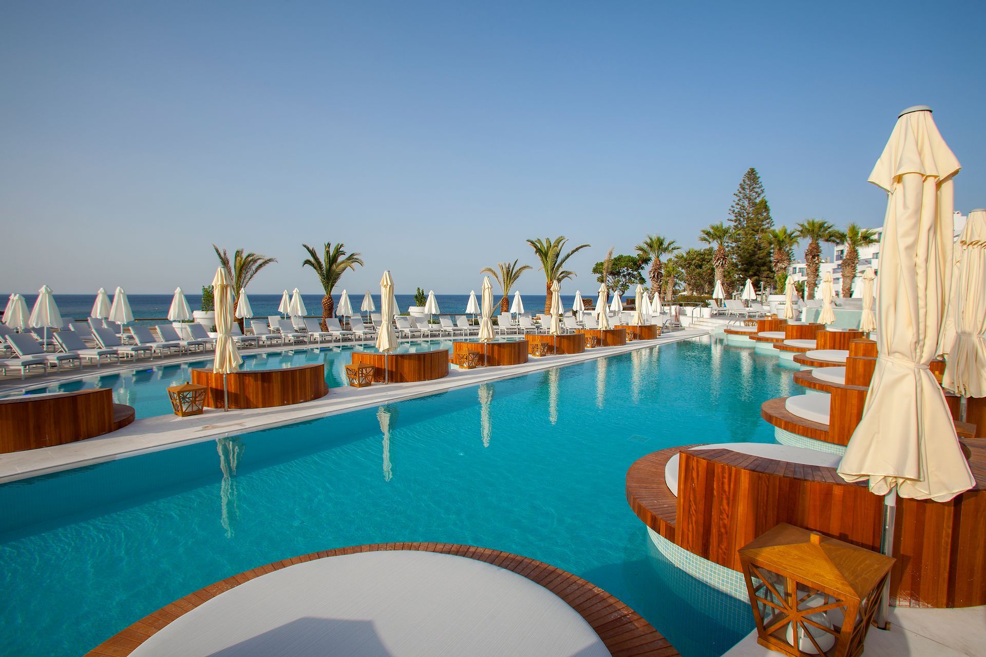 Poolside resort with turquoise water, white umbrellas, and ocean view.