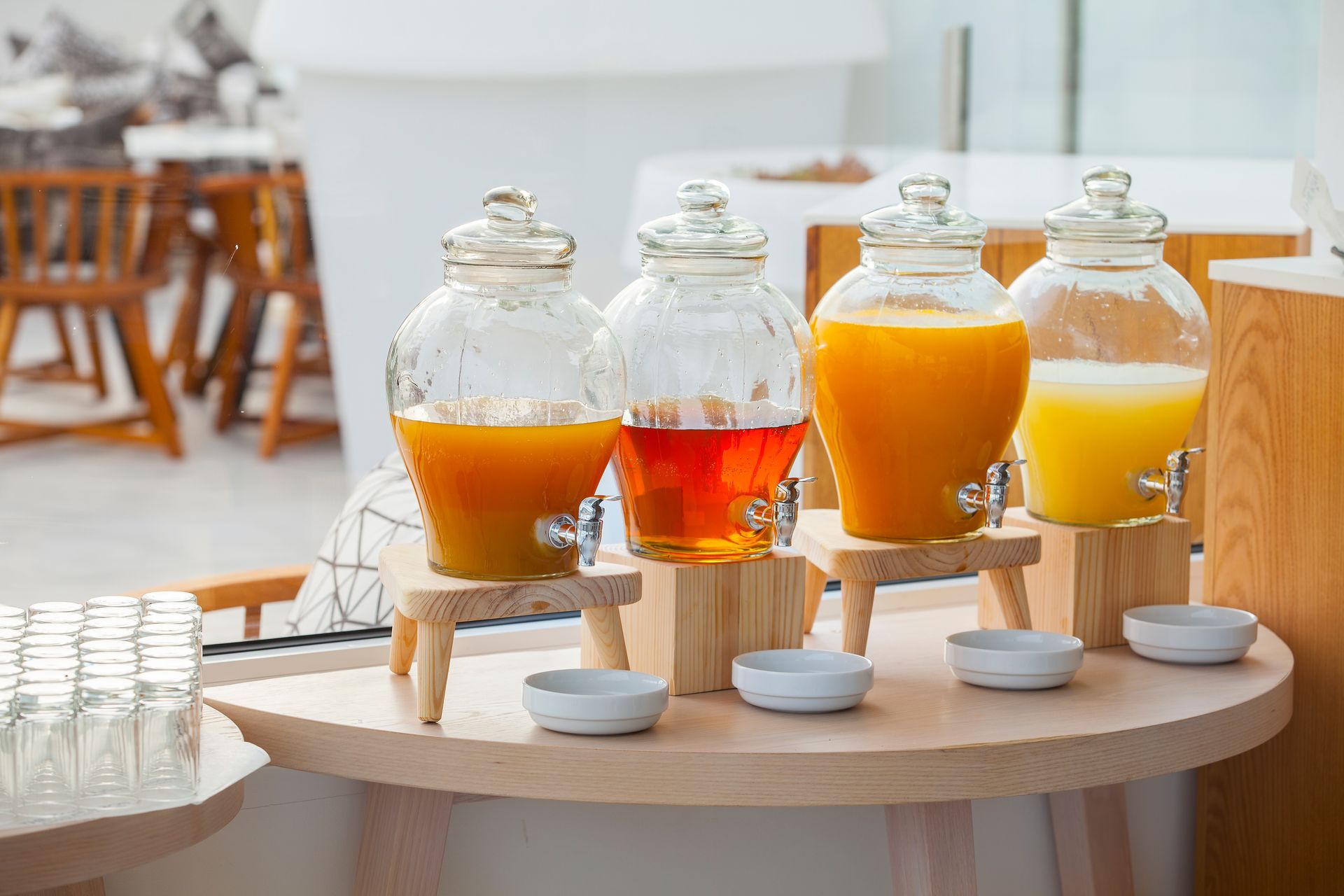 Juice dispensers with various fruit juices on a wooden buffet table.
