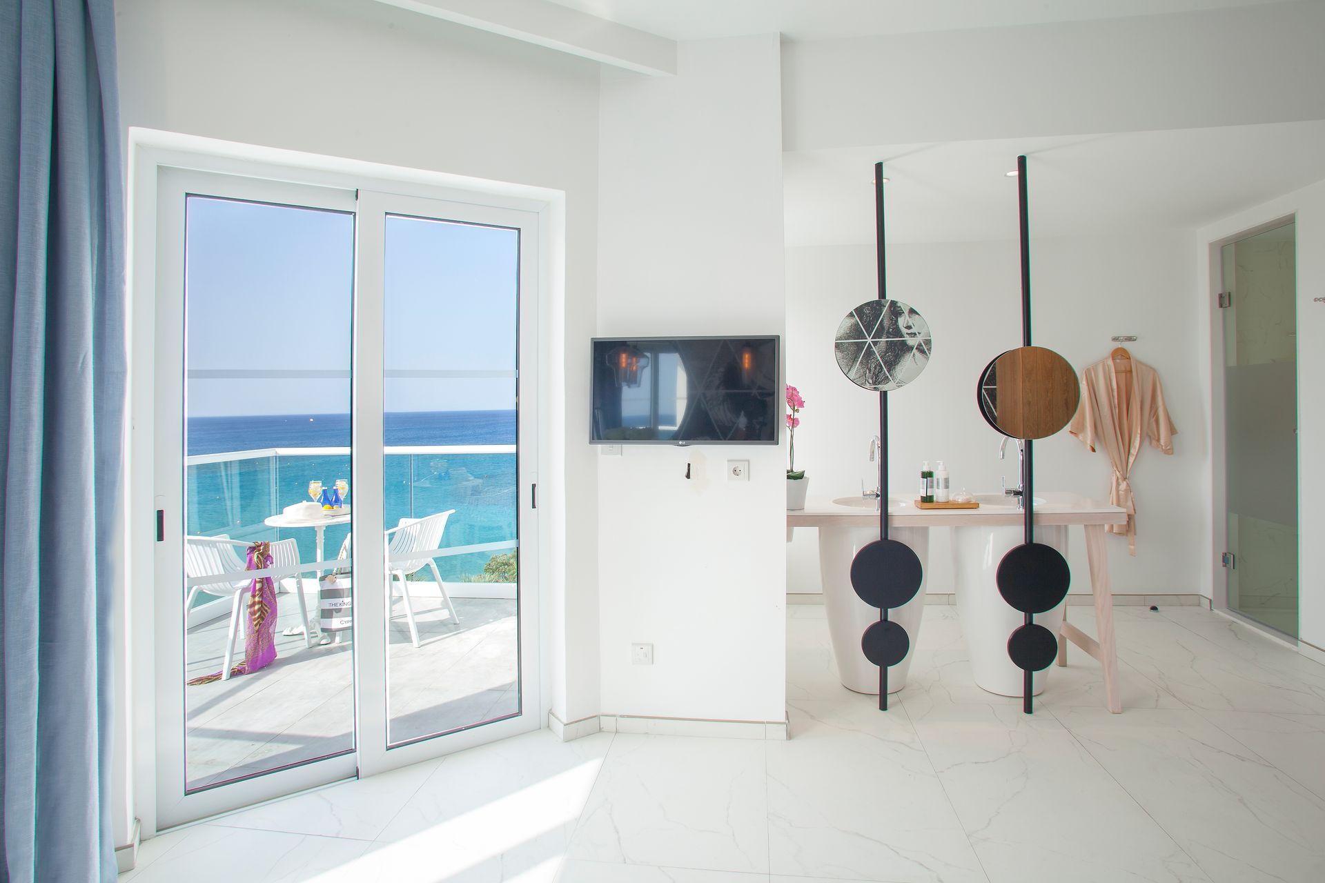 King Jason Protaras with sea view through sliding doors; TV, and decorative room divider.