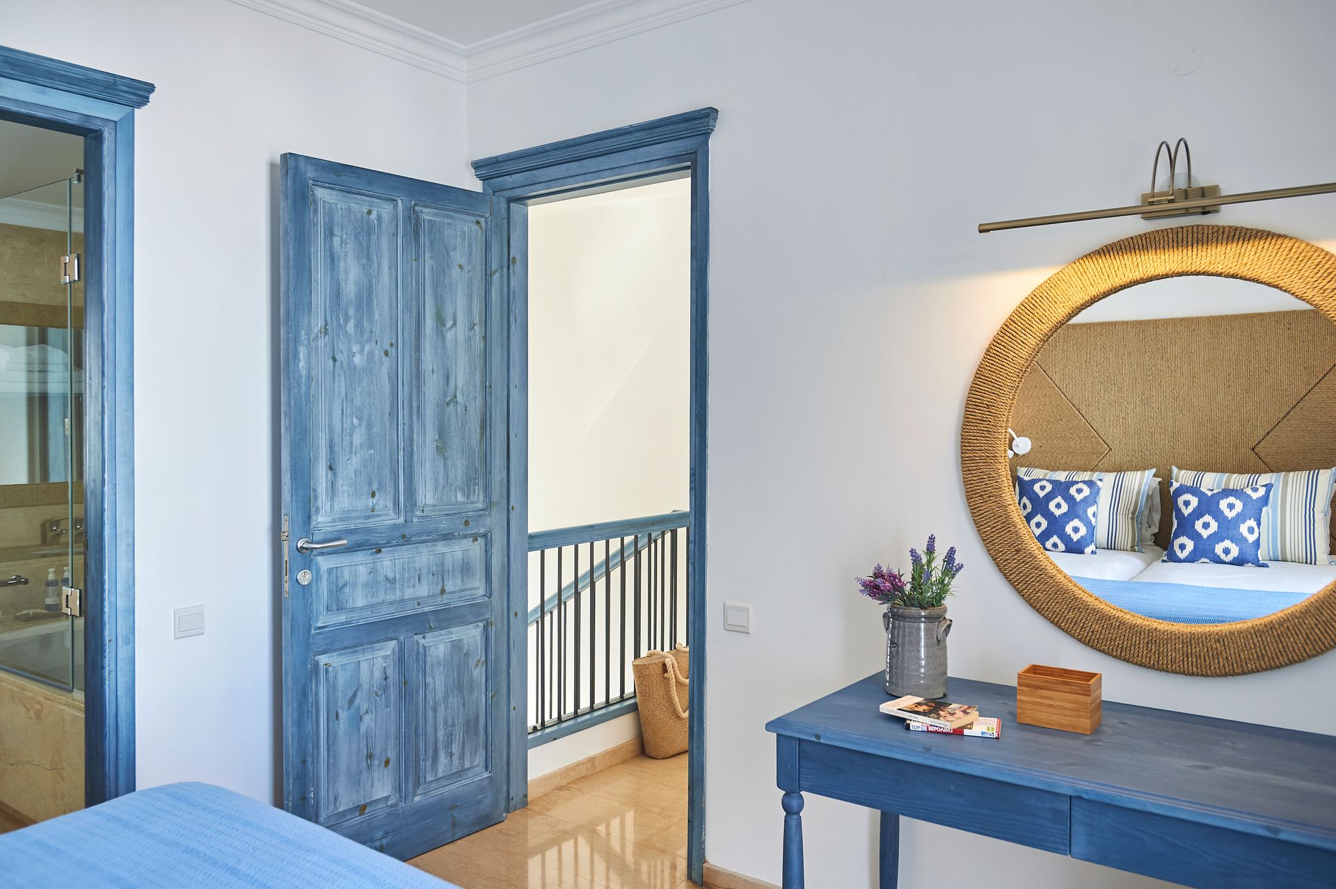 Bedroom interior with blue doors, a round mirror, and a table with flowers.