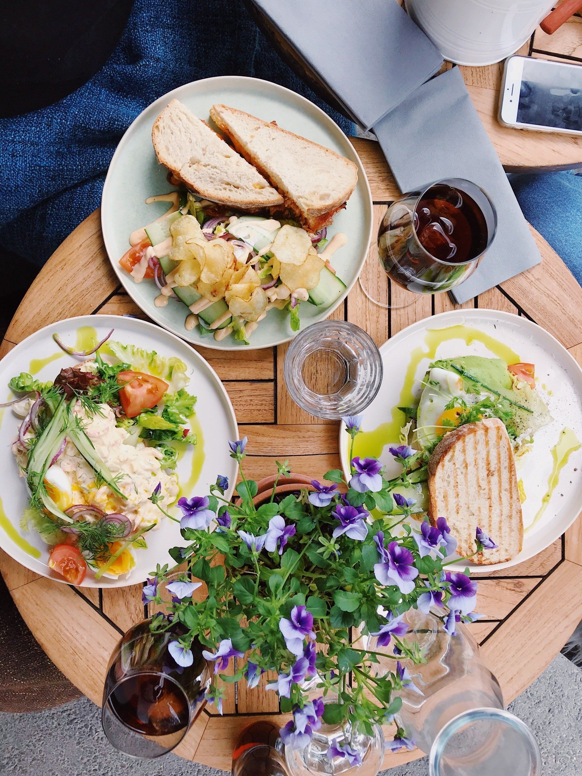 A wooden table topped with plates of food and flowers.