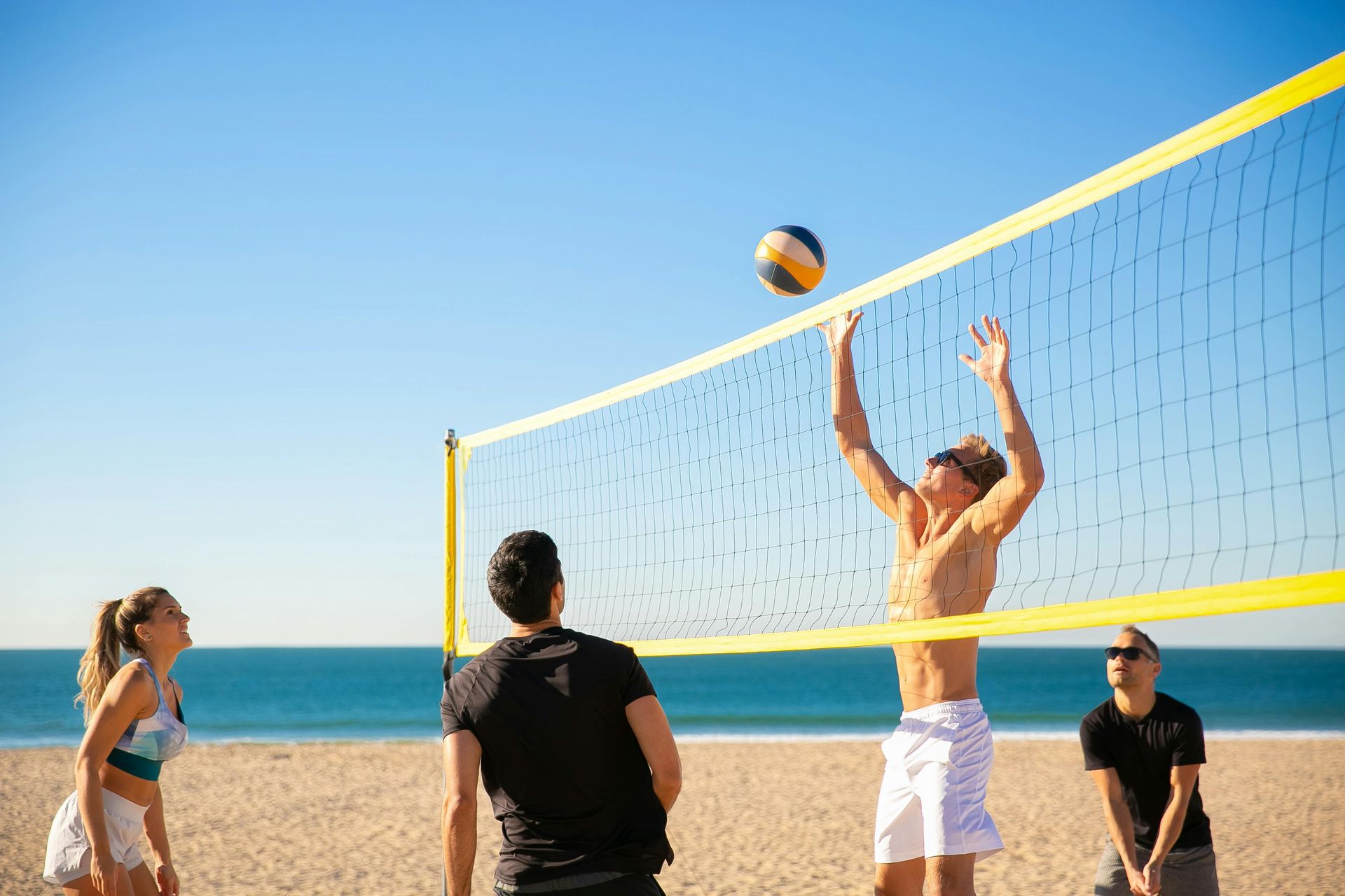 A group of people are playing volleyball on the beach.